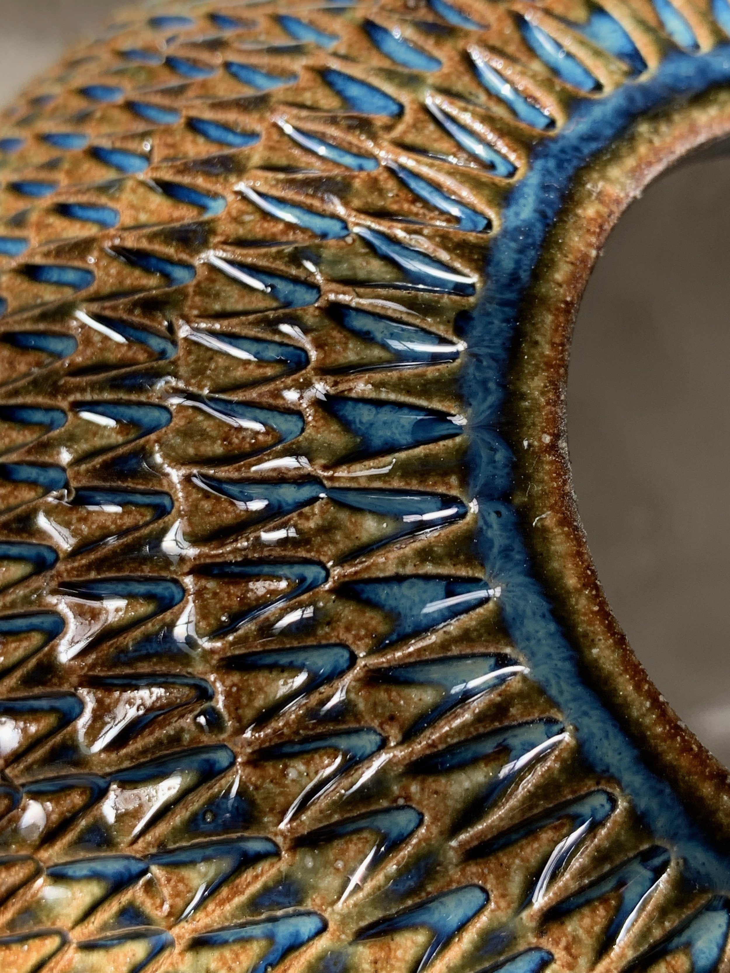 Close-up of a vintage metal hairbrush with a rusted surface and blue accents, showing detailed teeth.