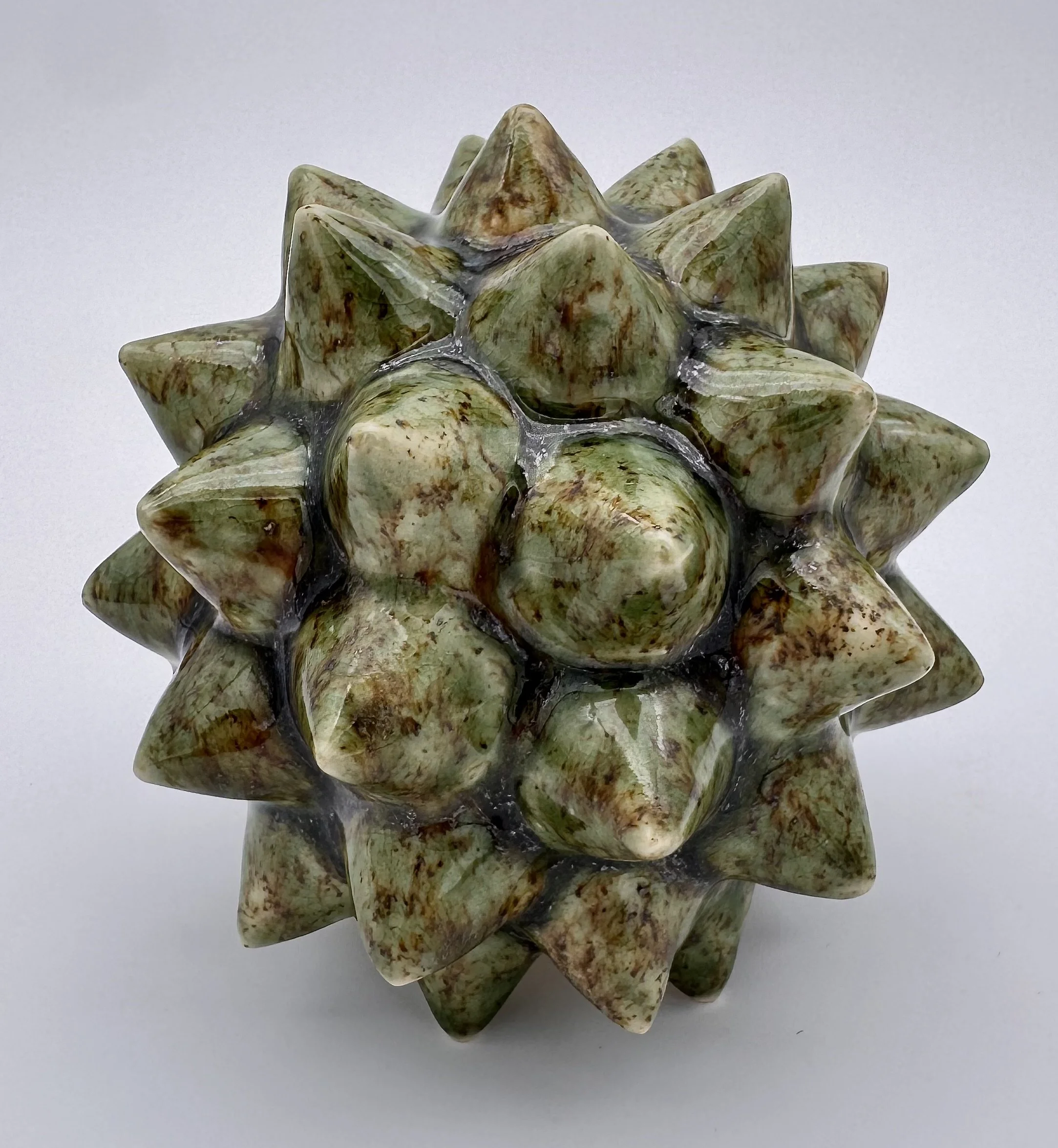 A cluster of polished green and brown marbled coral or stone fossils arranged together against a plain white background.