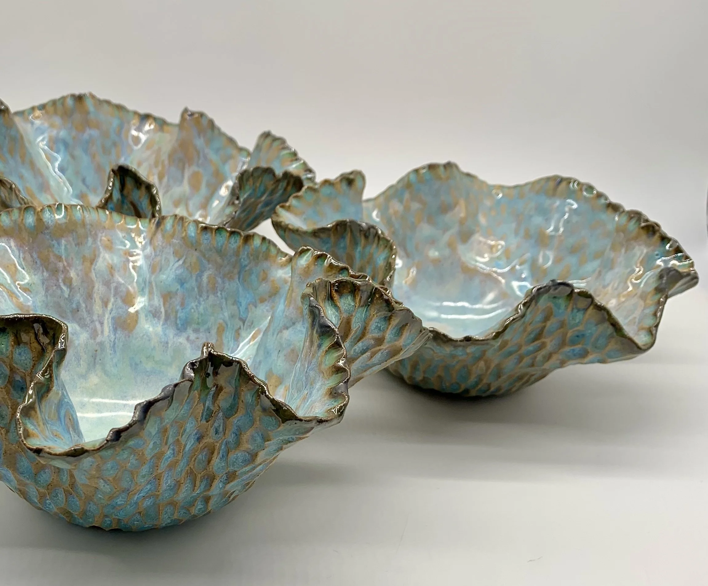 Two decorative ceramic bowls with a blue and gold iridescent glaze on a white surface.