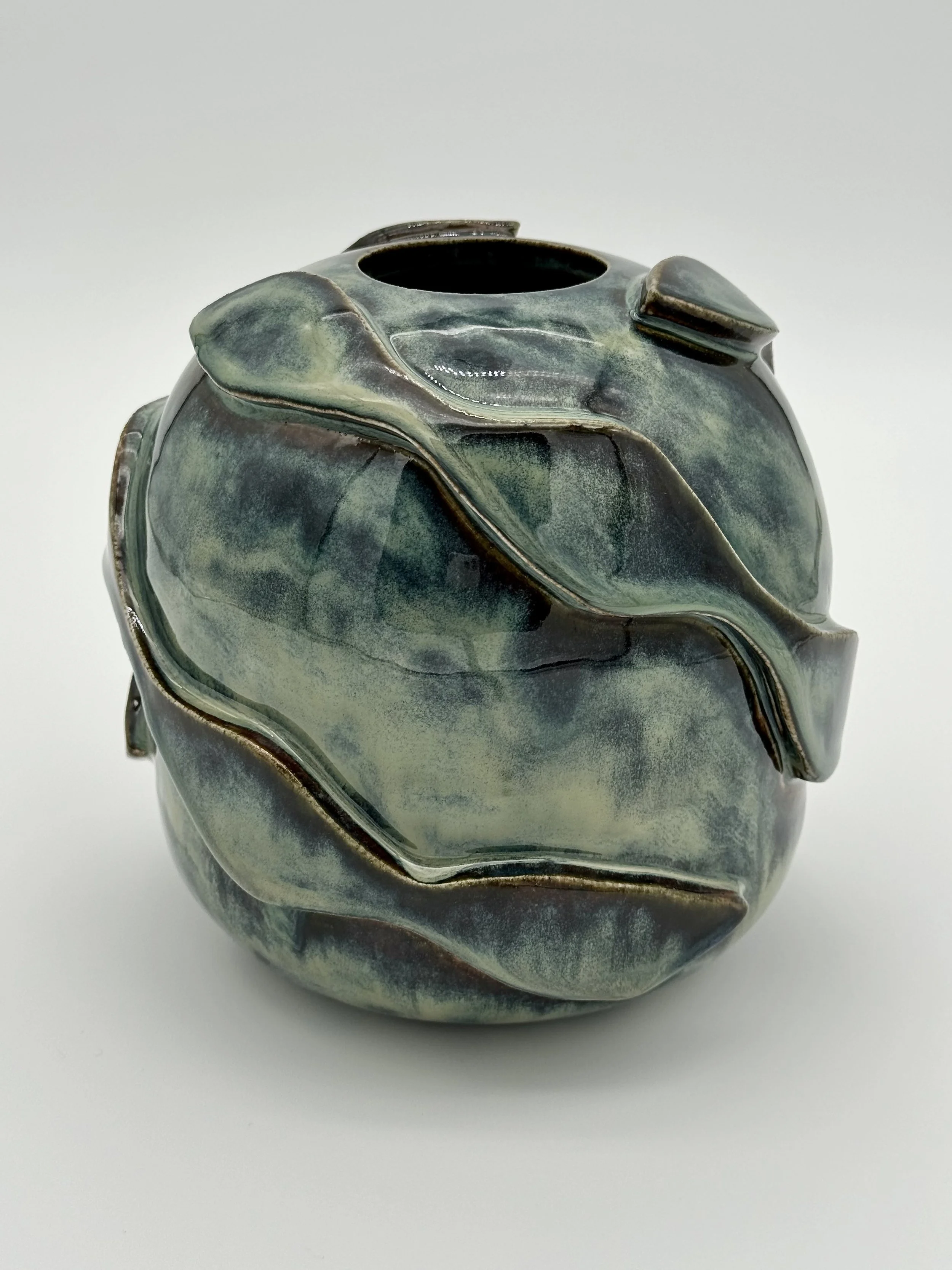 A ceramic vase with a glossy finish, featuring a fluid, abstract design in shades of green, blue, and brown, on a white surface.