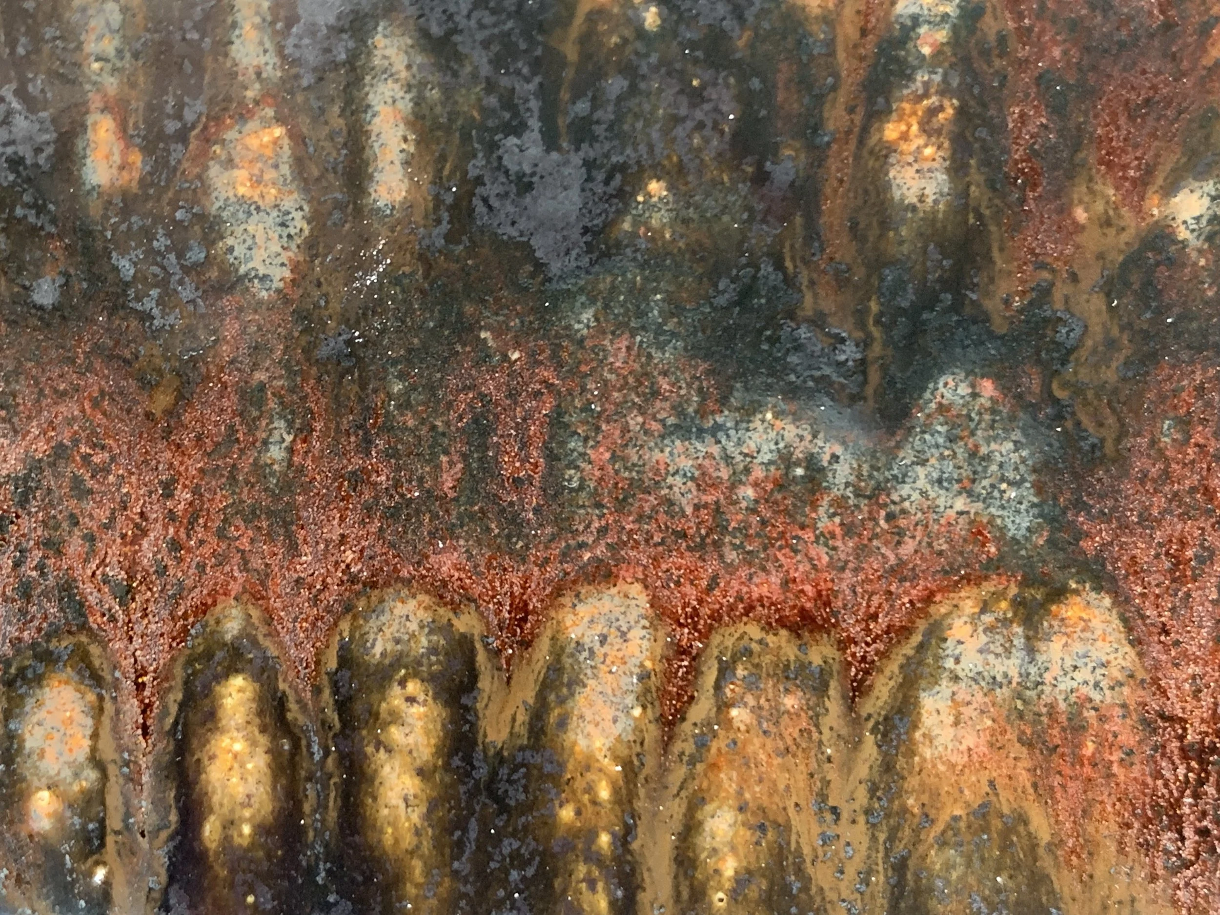 Close-up of a rusty, weathered metal surface with various shades of orange, brown, and gray, showing corrosion and textured patches.