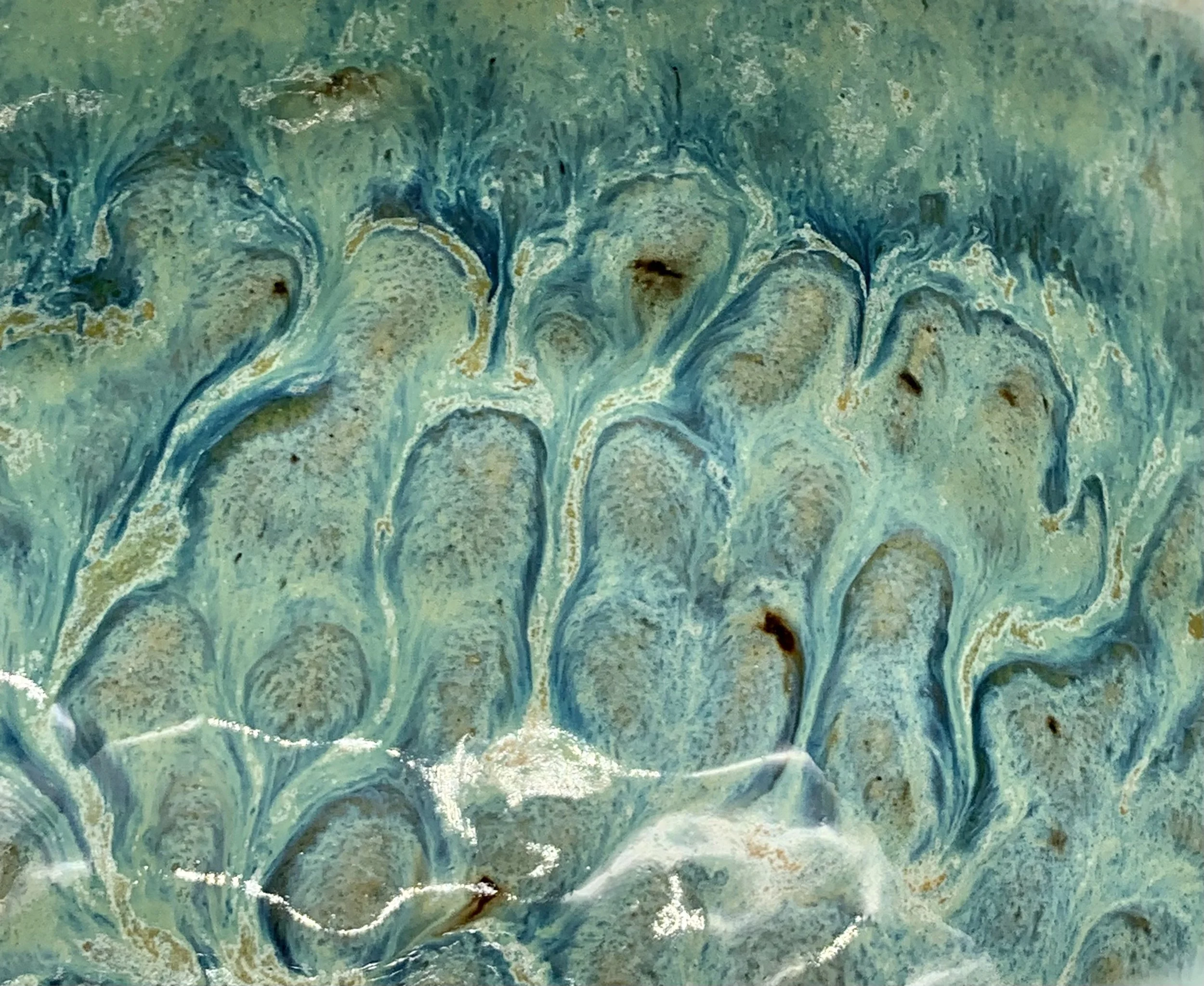 Close-up of a textured turquoise and gold marble surface with swirling patterns.