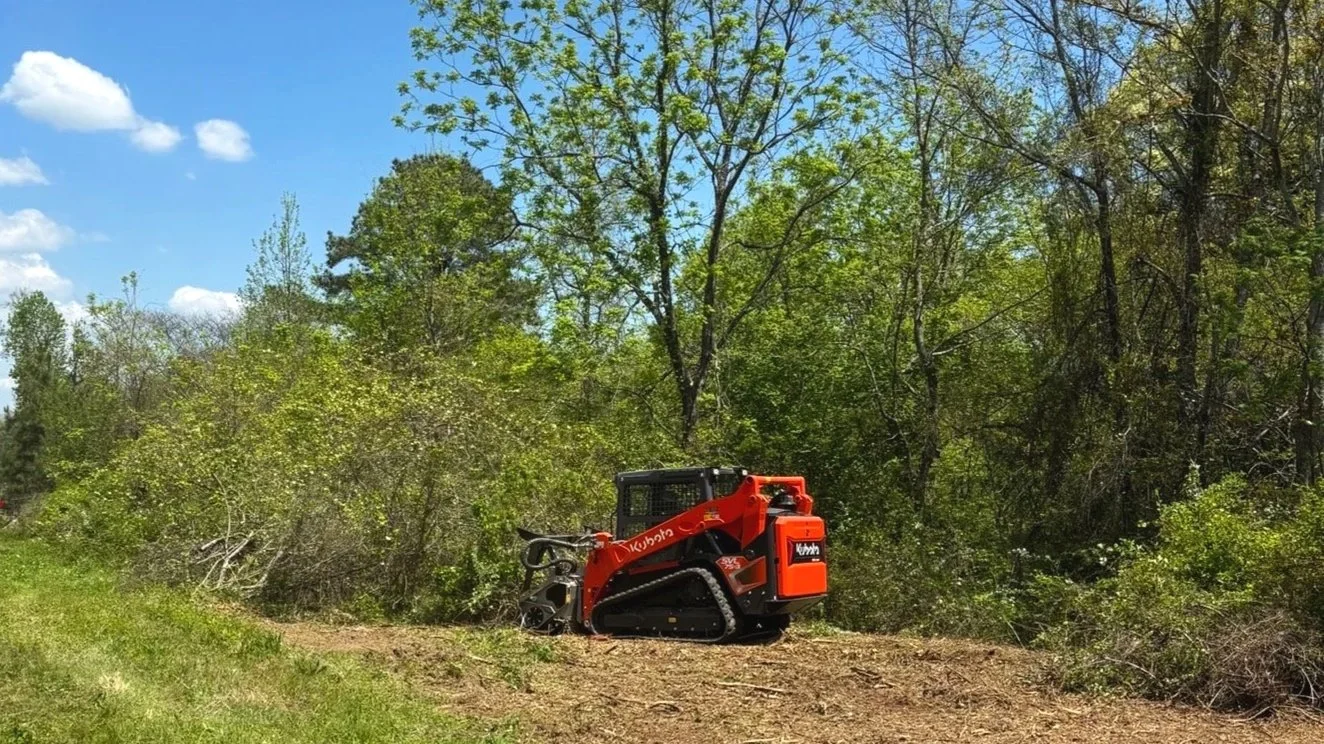 Track loader clearing brush