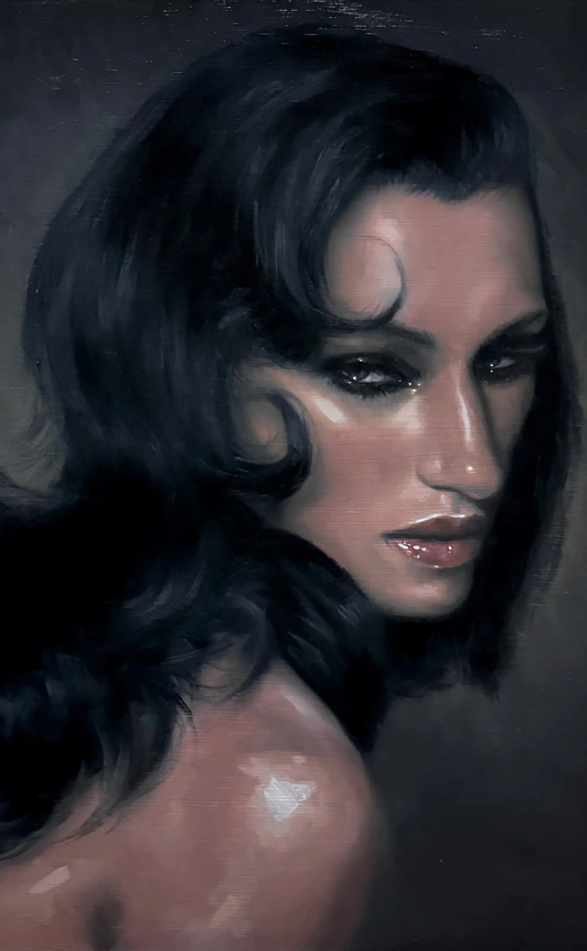 Close-up of a woman with dark, wavy hair and makeup, looking directly at the camera.