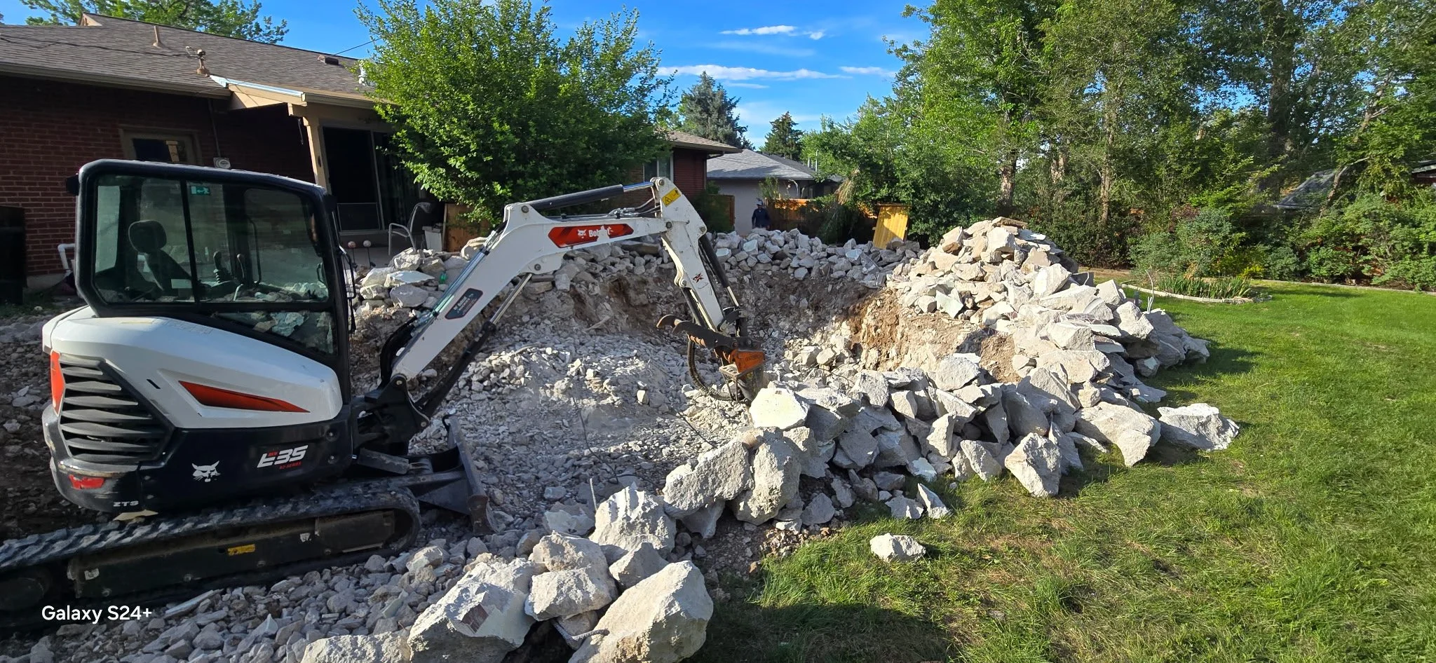 Elevation Hauling Co skid steer clearing concrete debris at a Denver job site