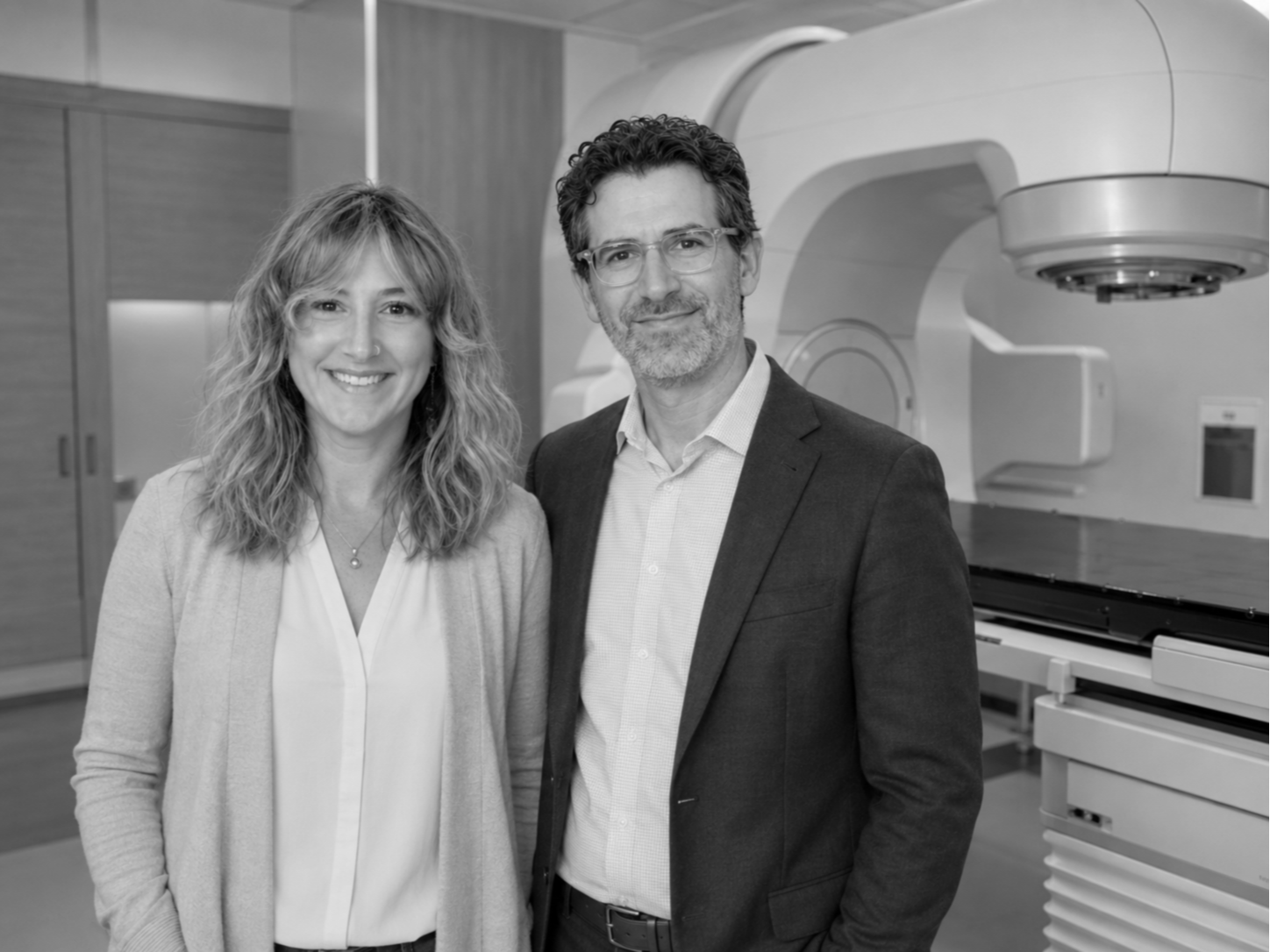 Black and white photo of a woman and a man standing together in a medical or research facility, with medical equipment in the background.
