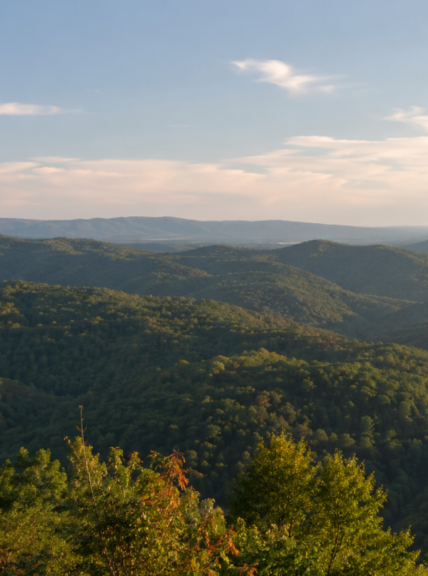 Scenic view of green rolling hills and mountains under a partly cloudy sky