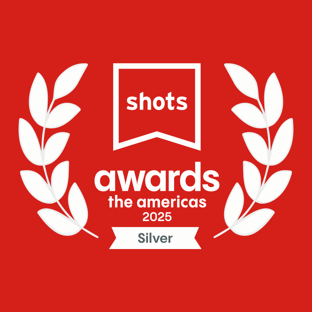 Award badge for shots awards the americas 2025, with laurel leaves on each side and a red background, indicating Silver level achievement.