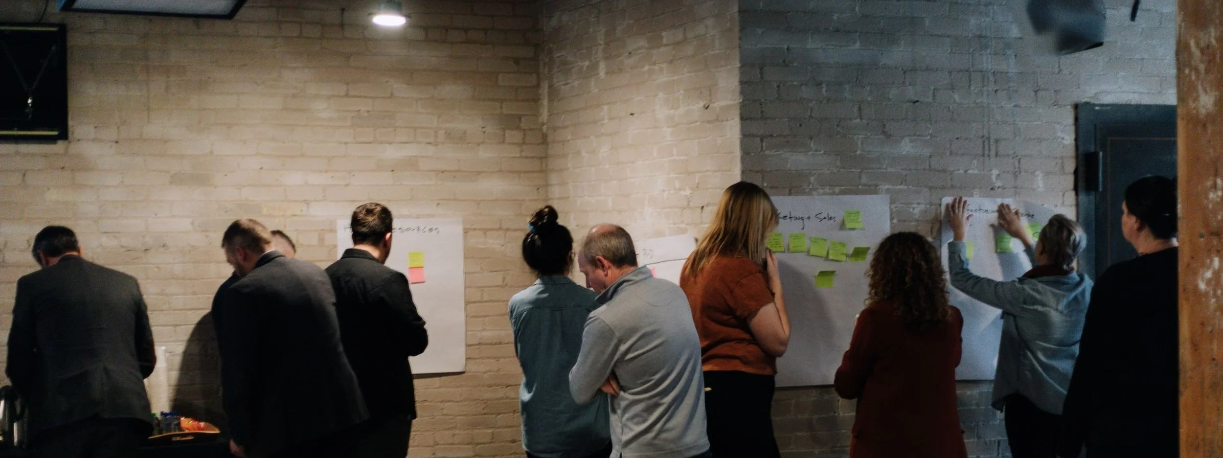 People gathering around large notepads and sticky notes on the walls.