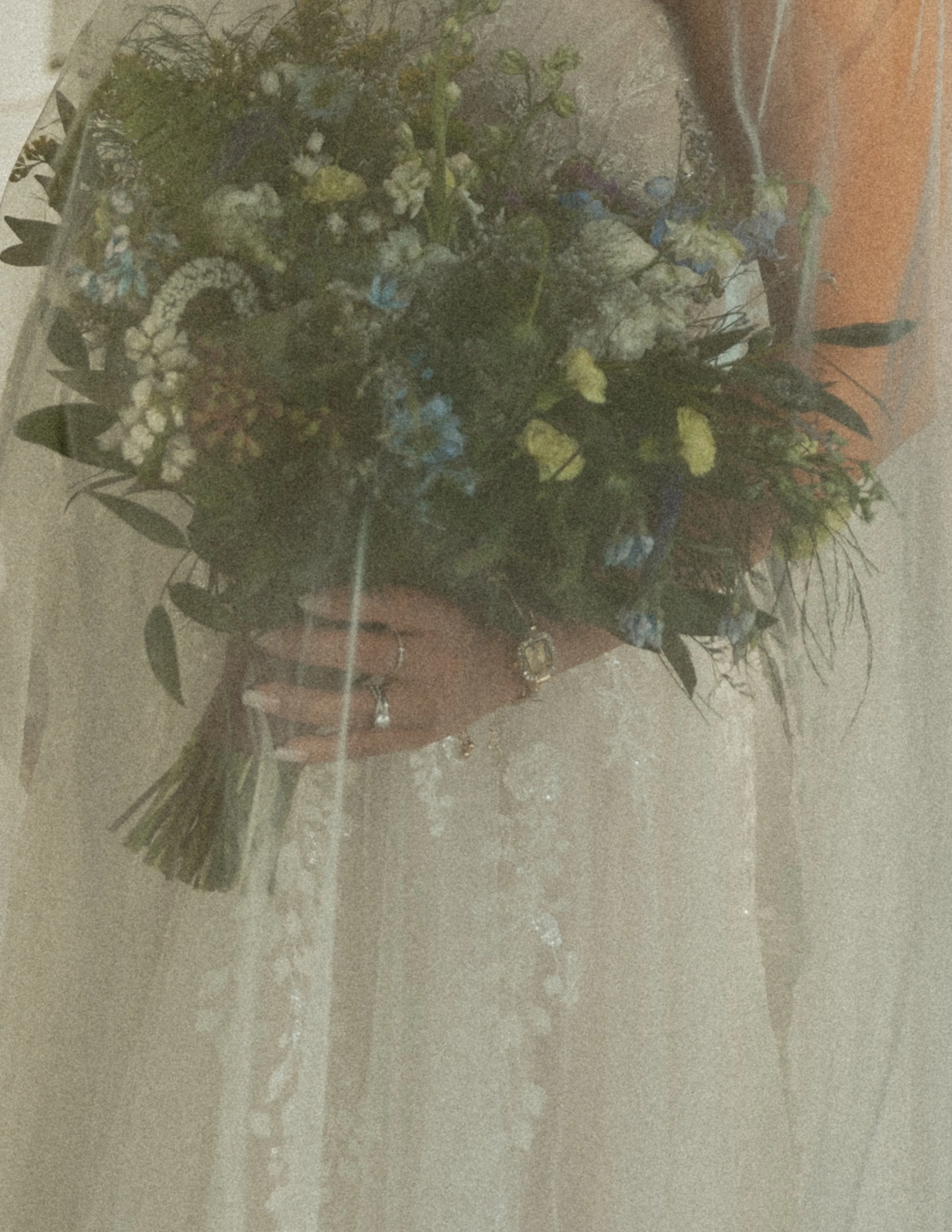 A bouquet of white, yellow, and light blue flowers wrapped in transparent cellophane and placed on a wooden surface.