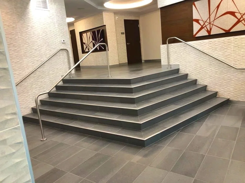 Indoor staircase with black steps, metal handrails, and modern artwork on the walls.