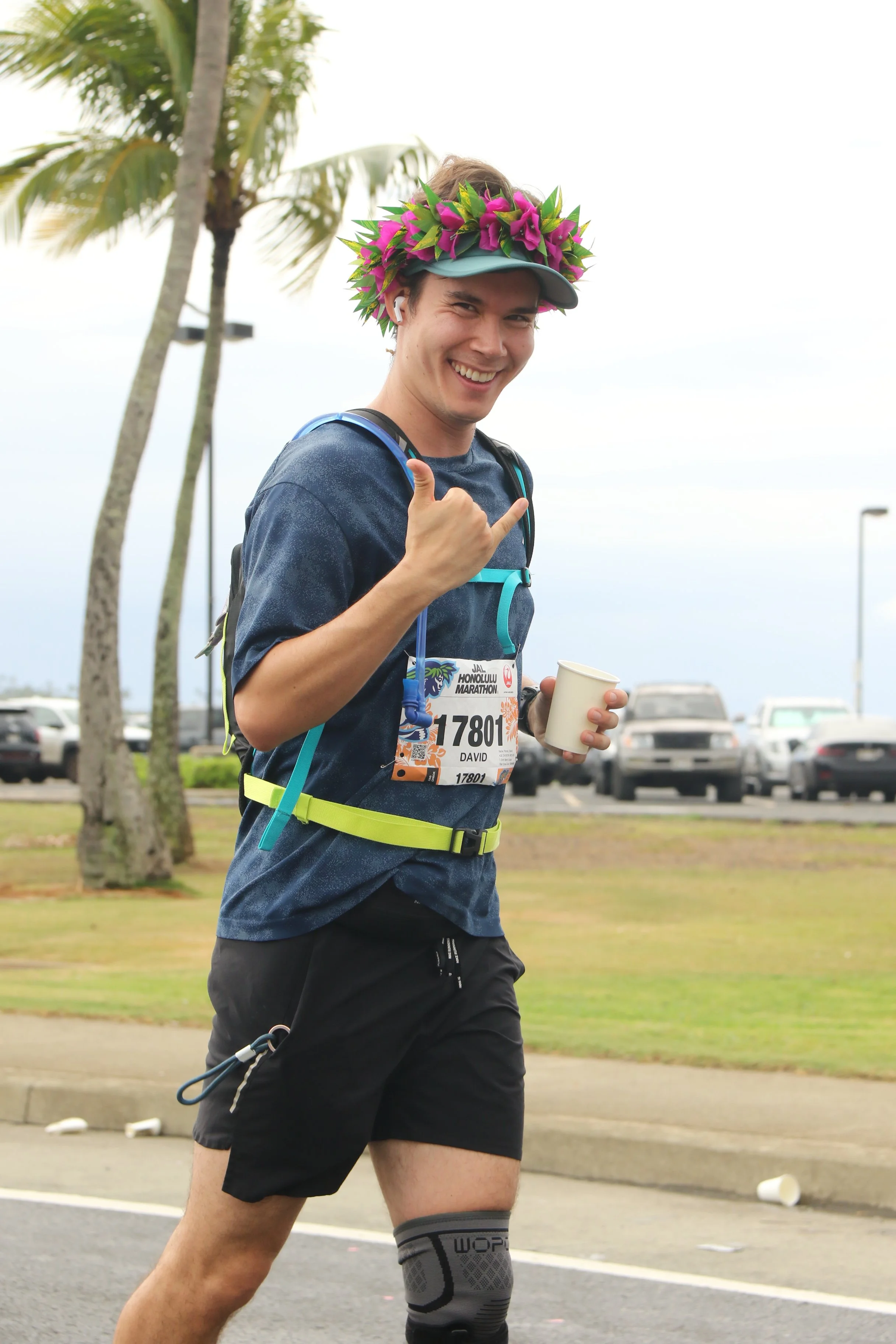 David Pierce smiles and gives a shaka while running a road race in Hawaiʻi.