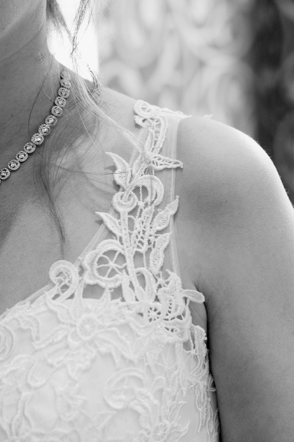 Nahaufnahme eines Brautkleids mit Spitzendetails und einer Perlenkette, Schwarz-Weiß-Foto.