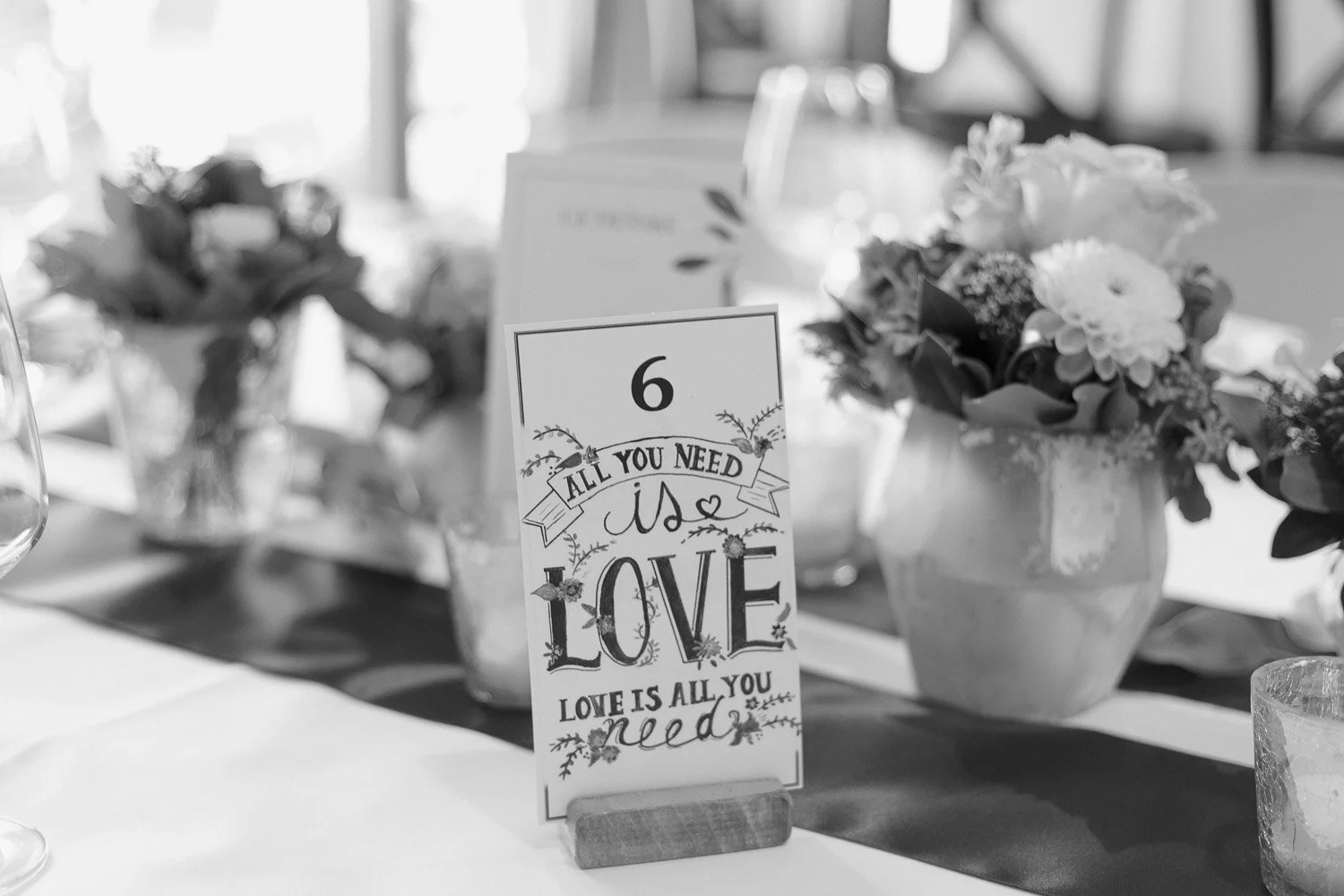 Schwarze und weiße Blumengestecke auf einem Tisch mit einer Tafel mit der Aufschrift 'All you need is love'