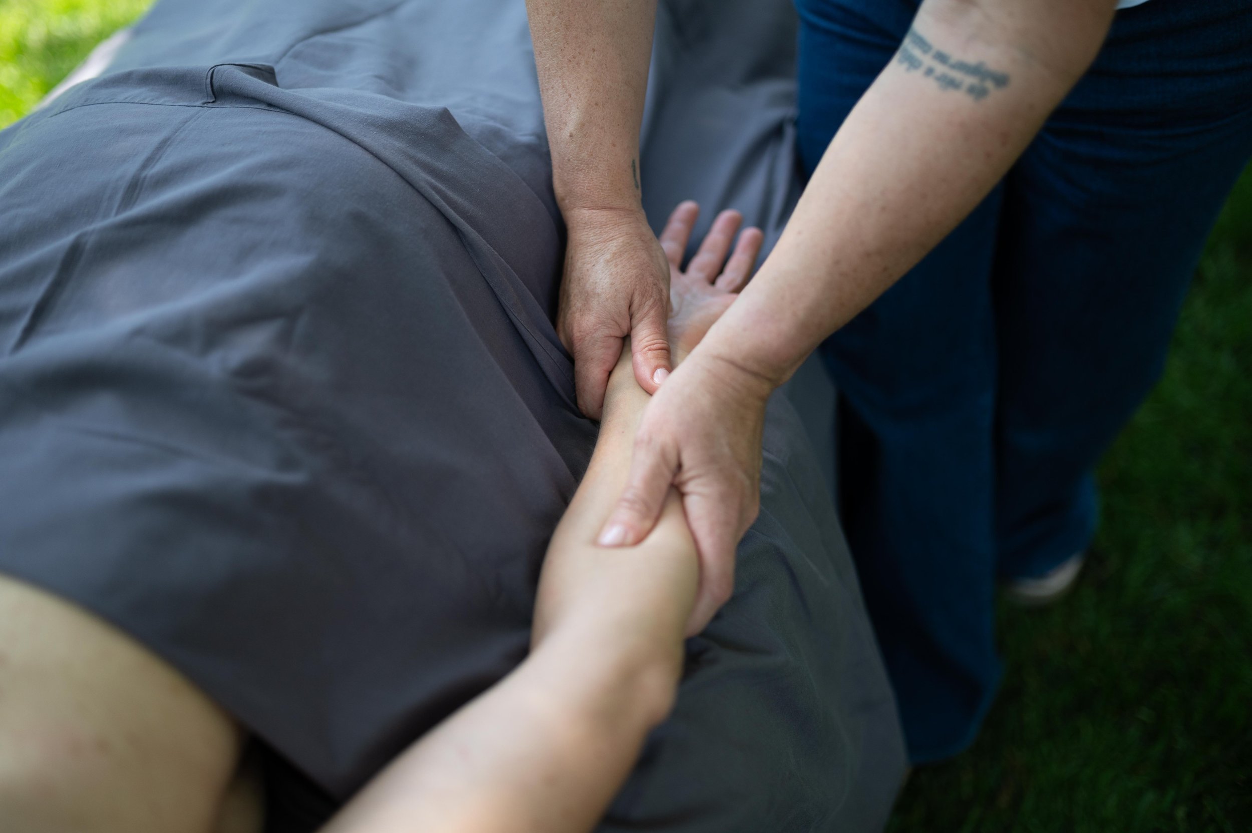 Person performing CPR on another person outdoors, with hands on their chest.