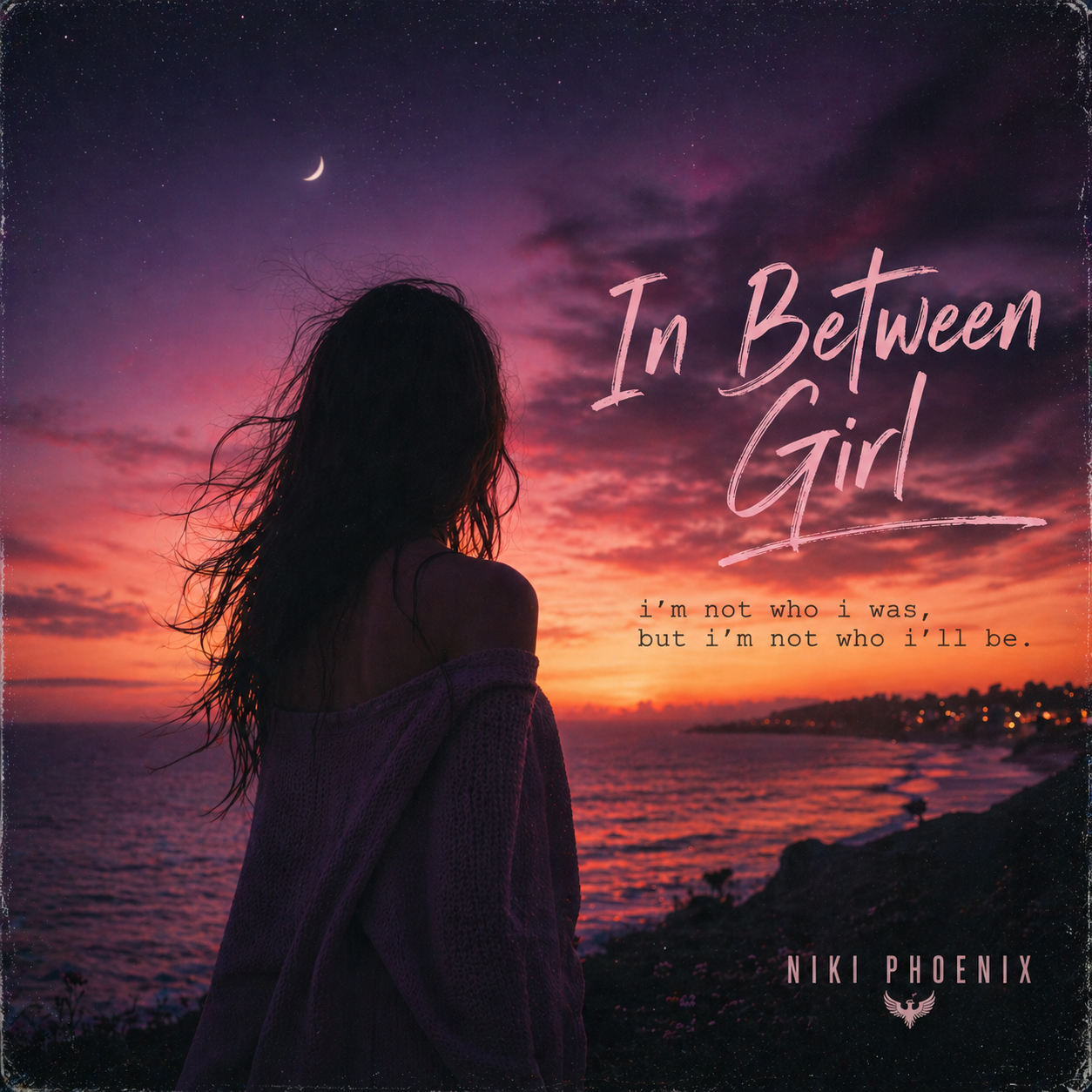 A woman with long hair looking at a colorful sunset over the ocean, with a crescent moon in the sky. Text overlay reads "In Between Girl," with a quote "I'm not who I was, but I’m not who I’ll be," and the name "Niki Phoenix."
