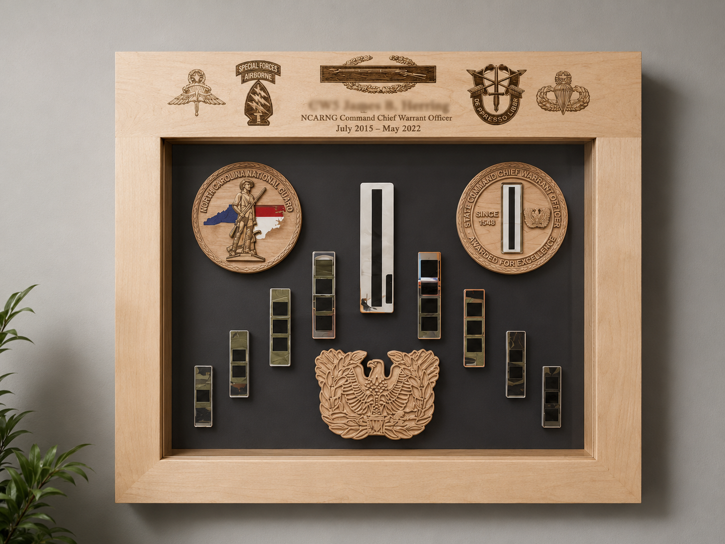 Display case featuring military medals, patches, and insignia, including North Carolina National Guard and North Carolina State Guard emblems, and a wooden plaque with military insignias and text.