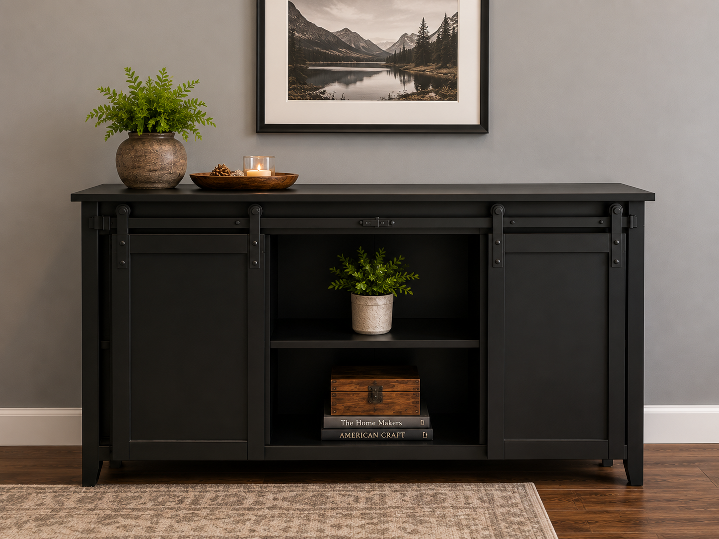 Black sideboard with decor including a potted plant, a wooden tray with pinecones and a candle, a picture of mountains on the wall, a smaller potted plant on the middle shelf, and books on the bottom shelf.