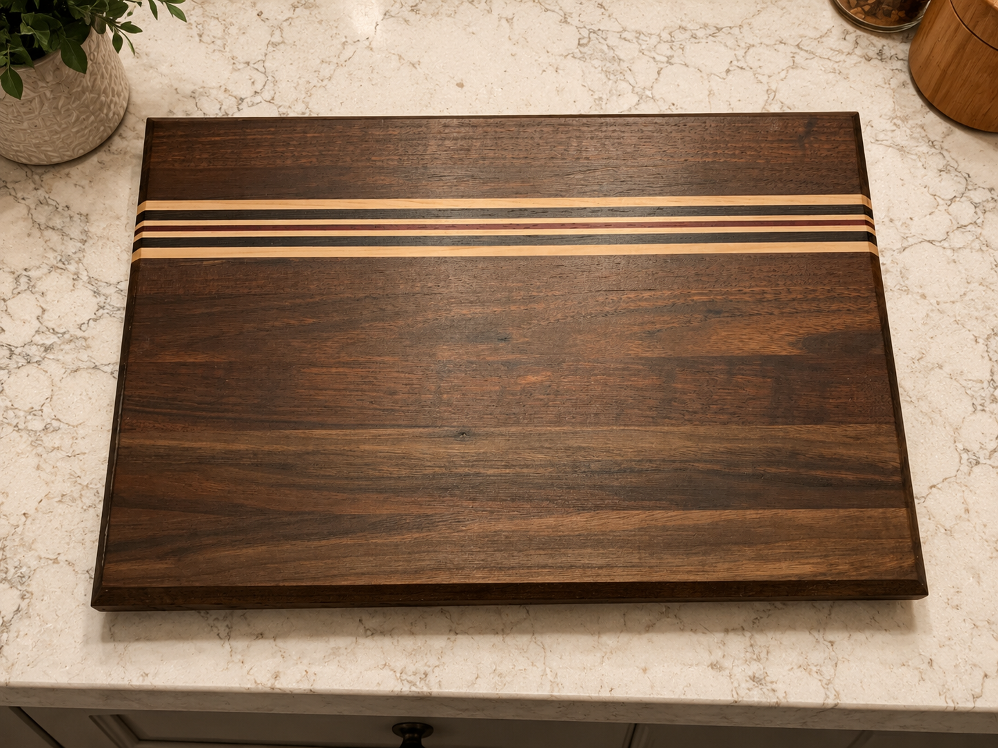A rectangular wooden board with a dark wood finish and five parallel lighter wood stripes across the top, placed on a granite countertop.