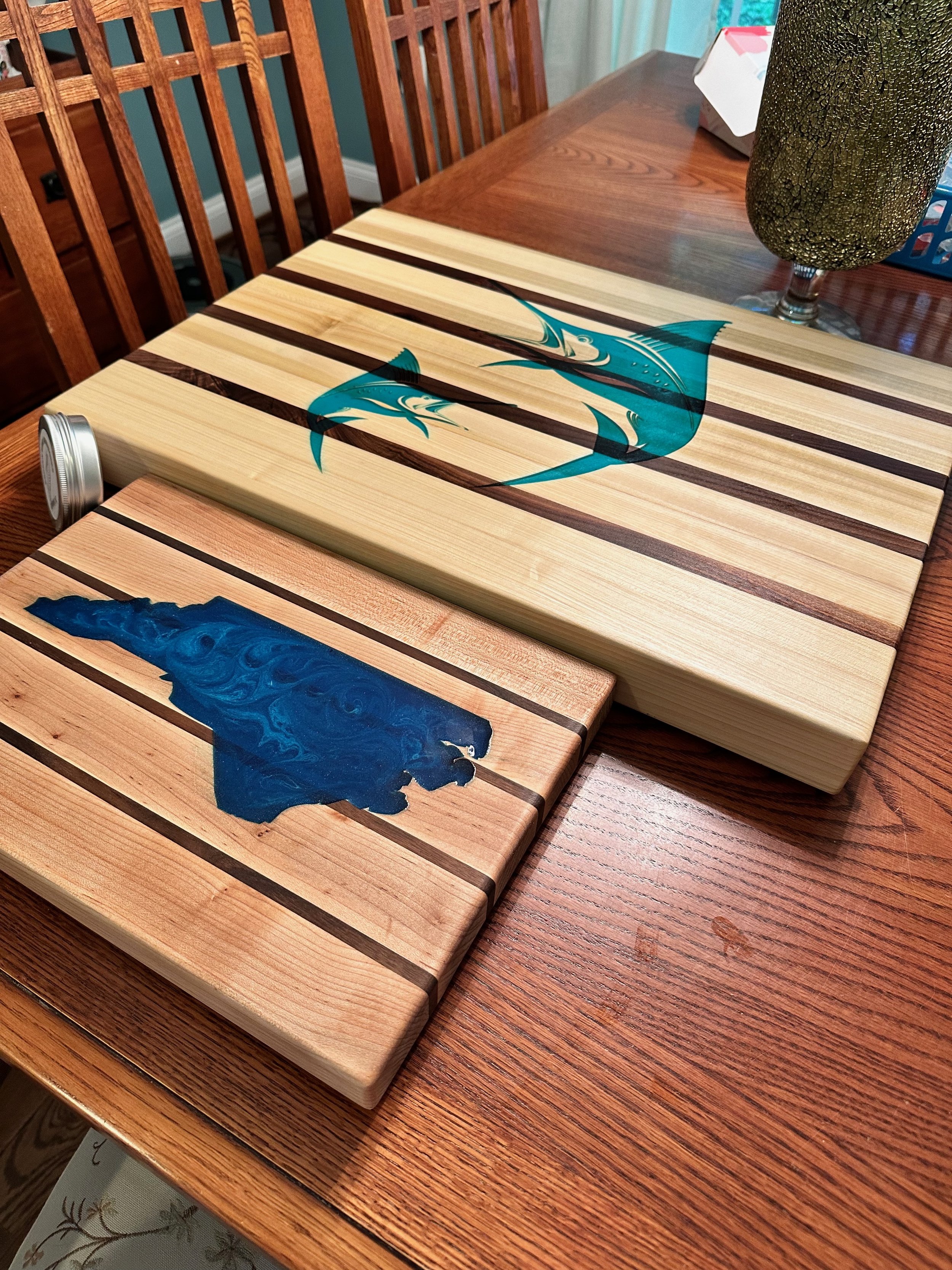 Two wooden cutting boards with painted sharks on them, placed on a wooden dining table.