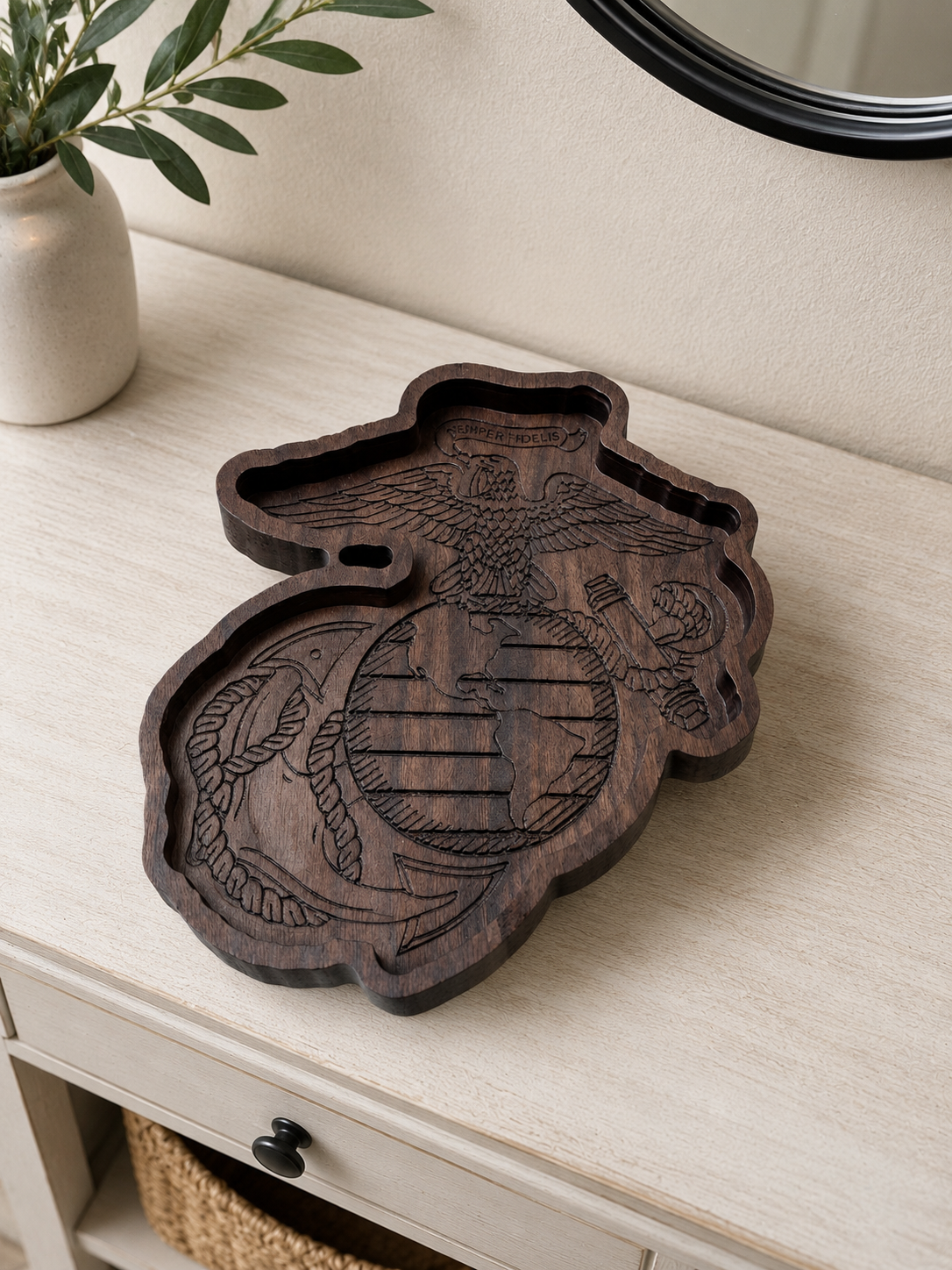 Wooden tray with the United States Marine Corps emblem, including an eagle, globe, and anchor, on a light-colored surface with a plant and mirror nearby.