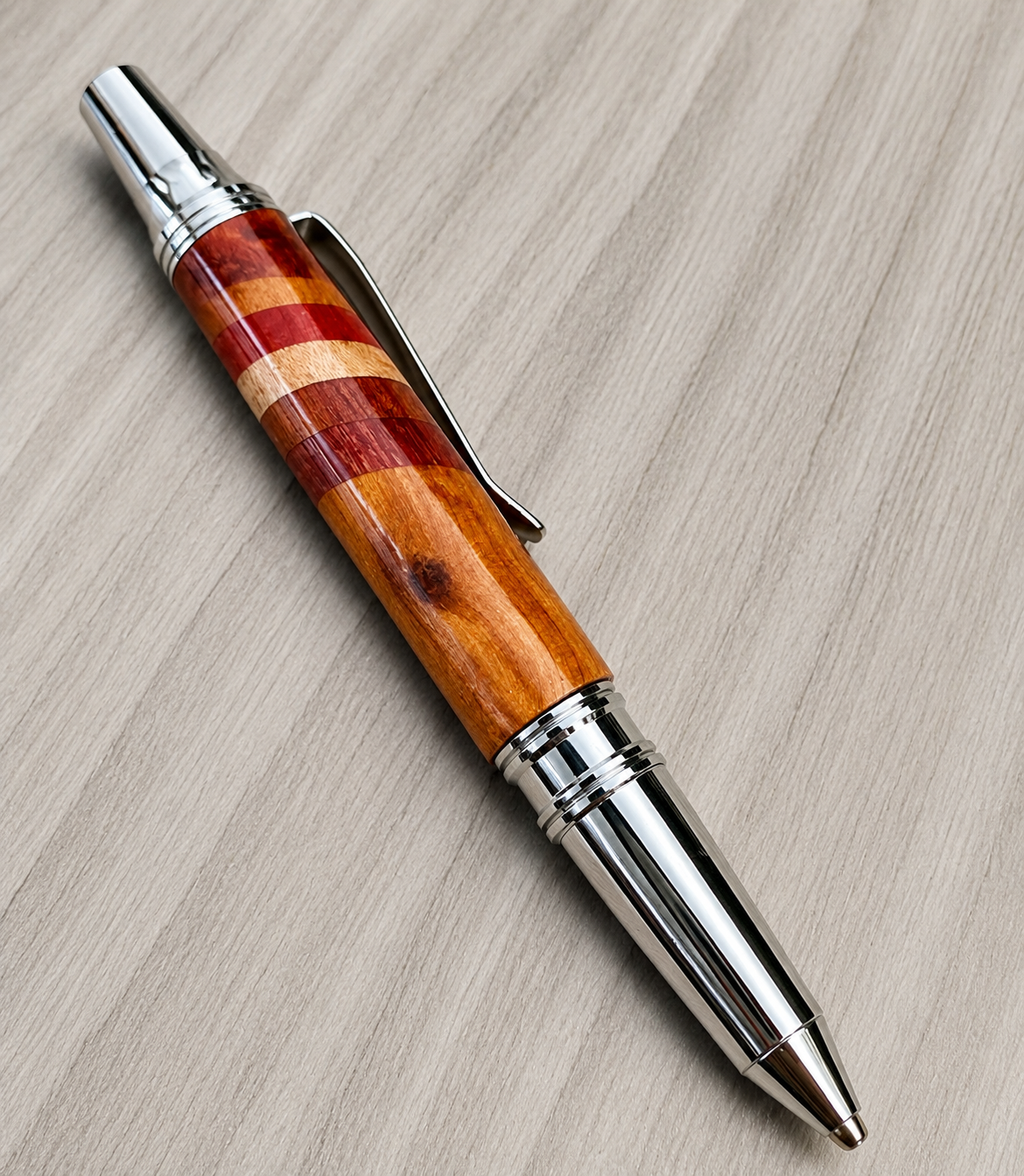 A wooden and metal ballpoint pen on a light wood surface.