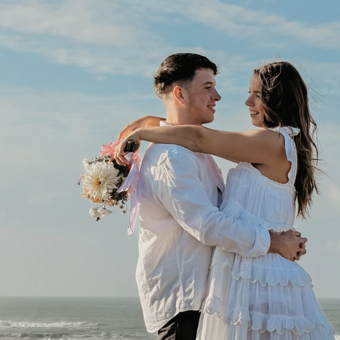An image of a young couple, newly engaged with a backdrop of the beautiful Cornish coast, an example of content creation for Cornish Diamond Co by Leah Croft