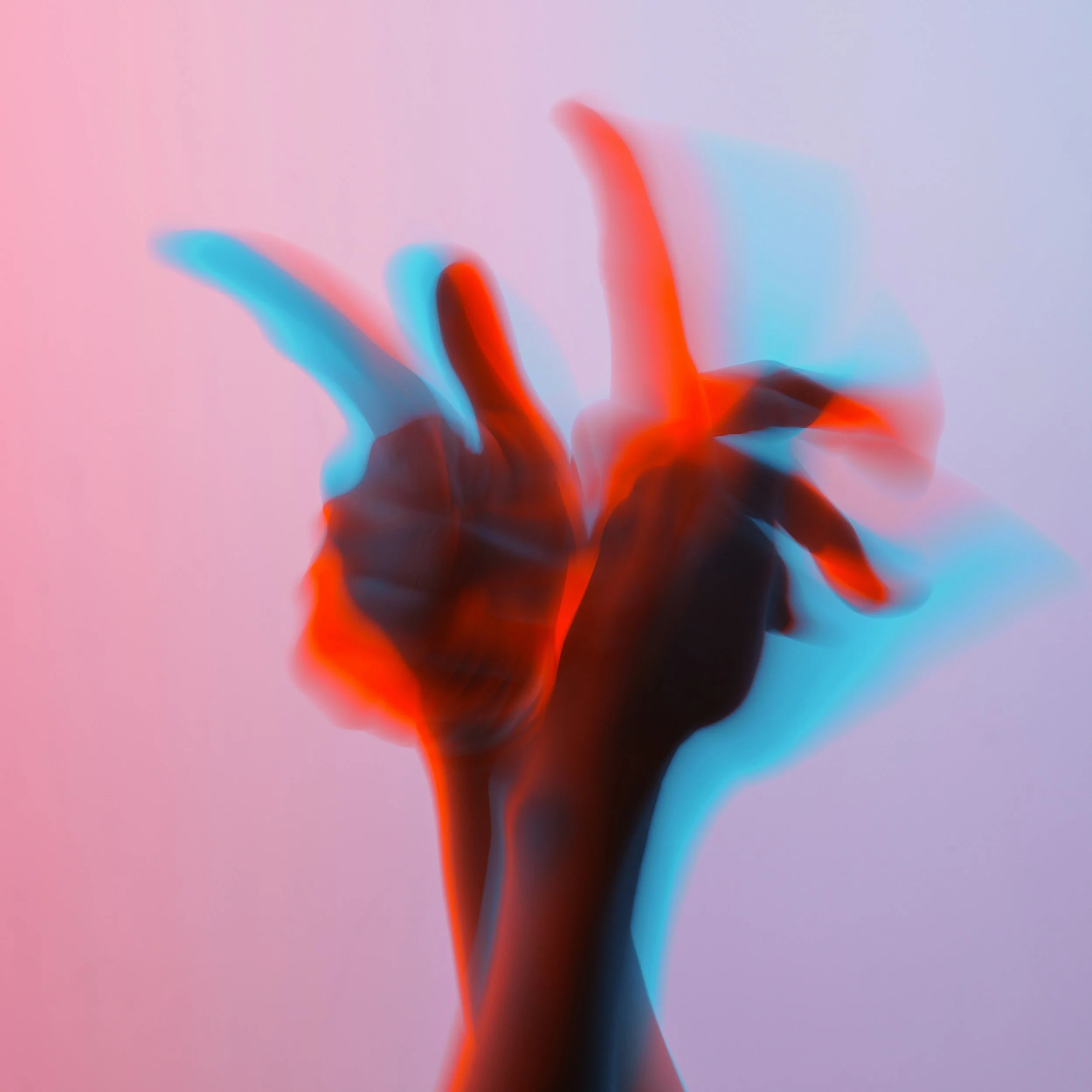 Abstract blurred image with red, blue, and black shapes on a pastel pink and purple background.