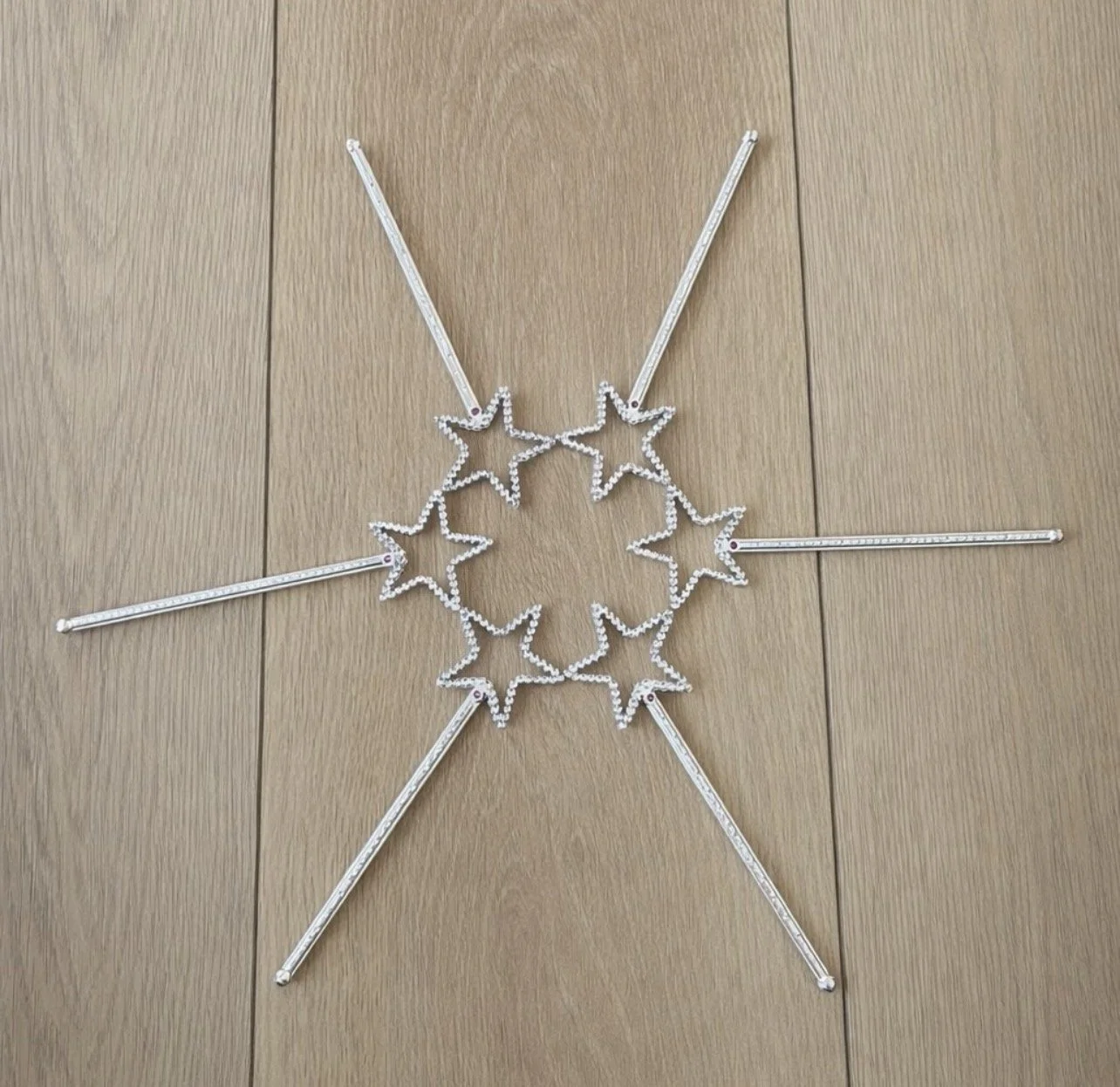 Star-shaped LED string lights arranged in a circular pattern on a wooden surface.