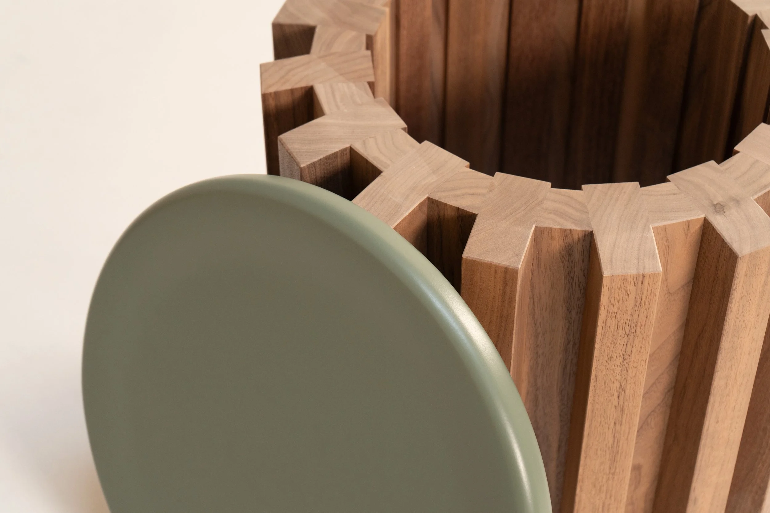 Close-up of a light green cup in the foreground, with a wooden item featuring a star pattern and a brown wooden barrel-shaped object in the background.