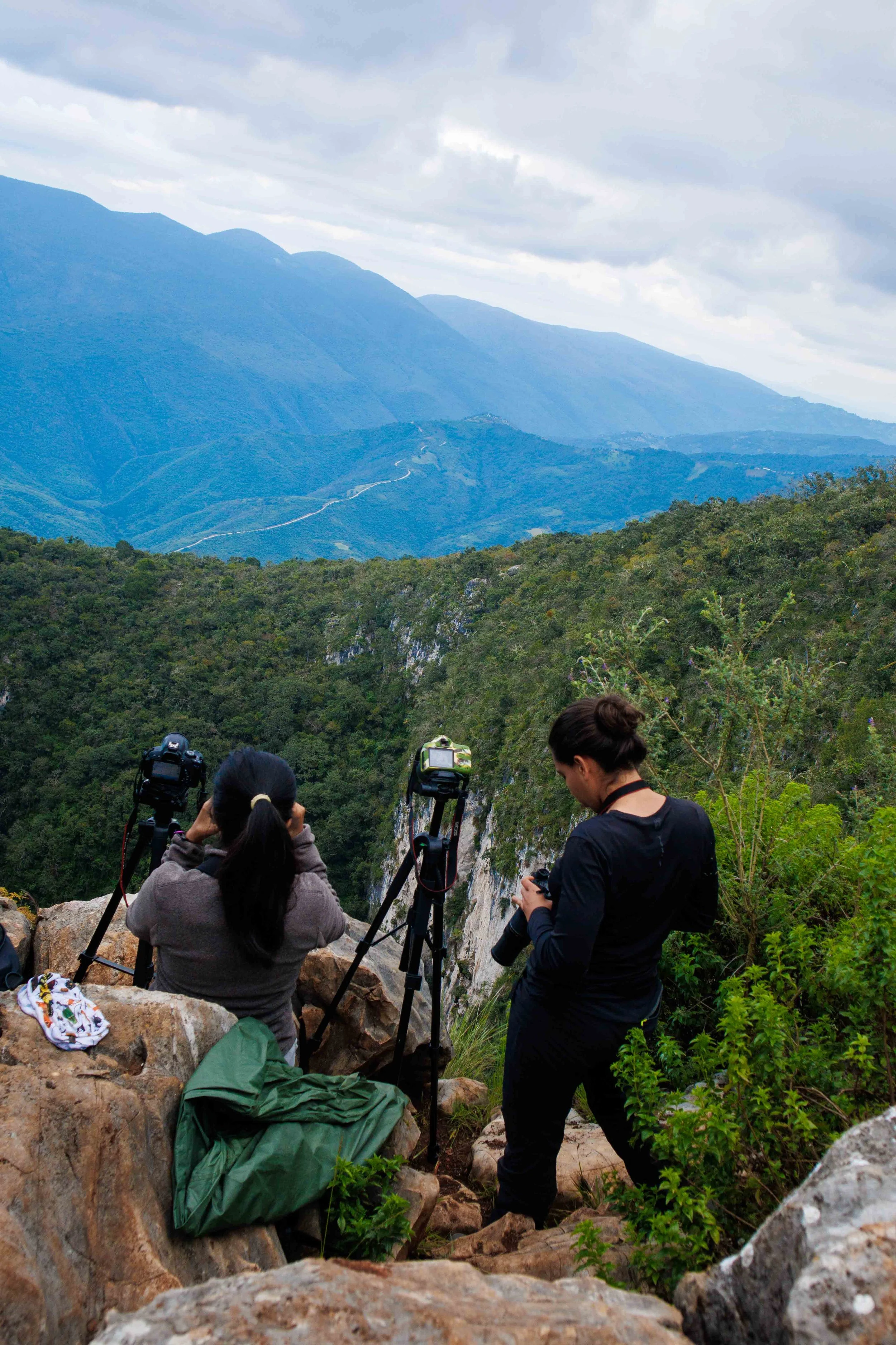 Grupo de personas en un mirador de montañas, algunas con cámaras, mirando hacia un paisaje de montañas y nubes, en un entorno natural Reserva de la biosferaSierra Gorda, Querétaro, Sótano del barro.