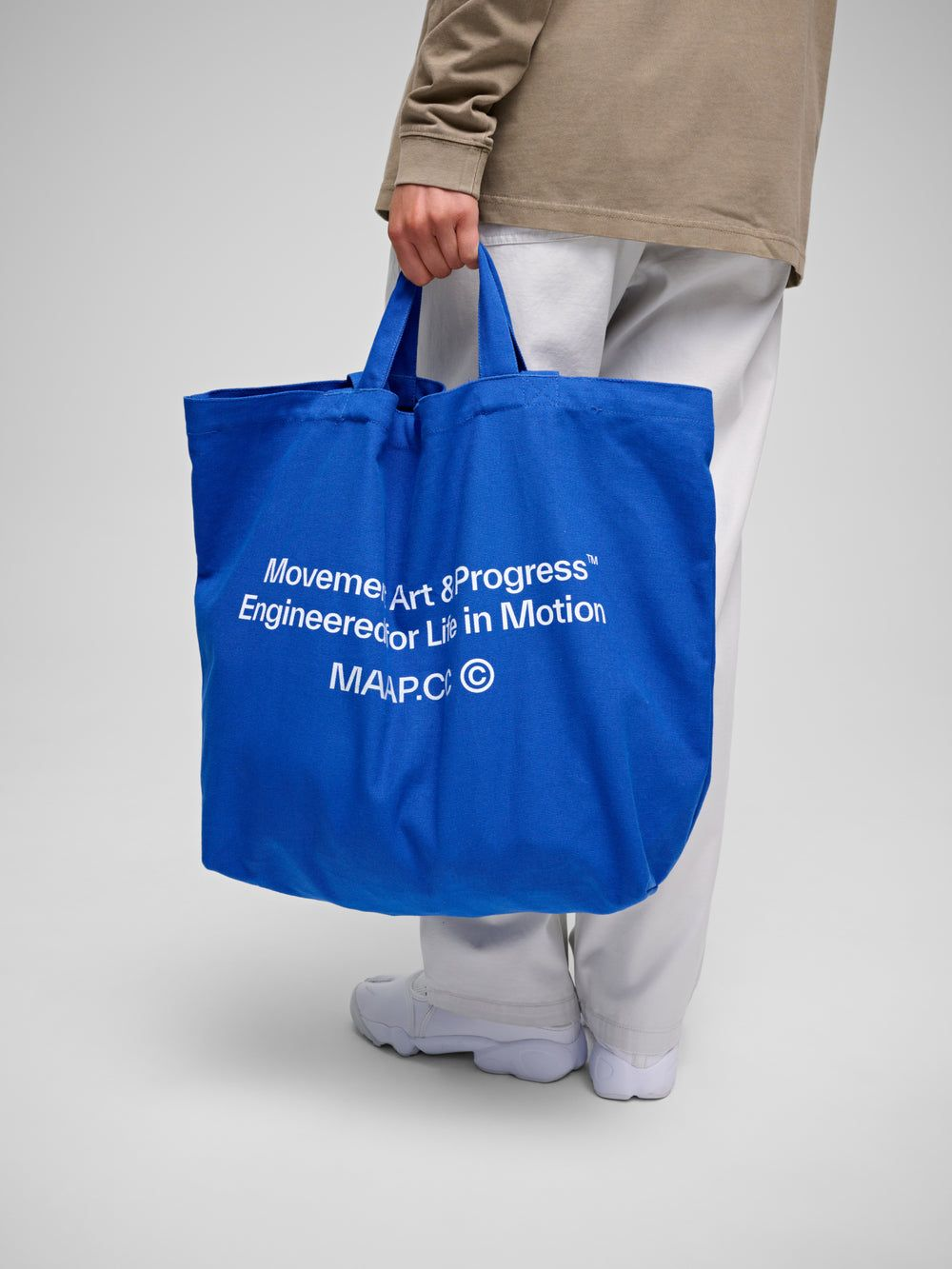 Bolsa de tela personalizada para marca, sostenida por una persona, con diseño impreso en color blanco sobre tela azul como ejemplo de producto promocional corporativo.
