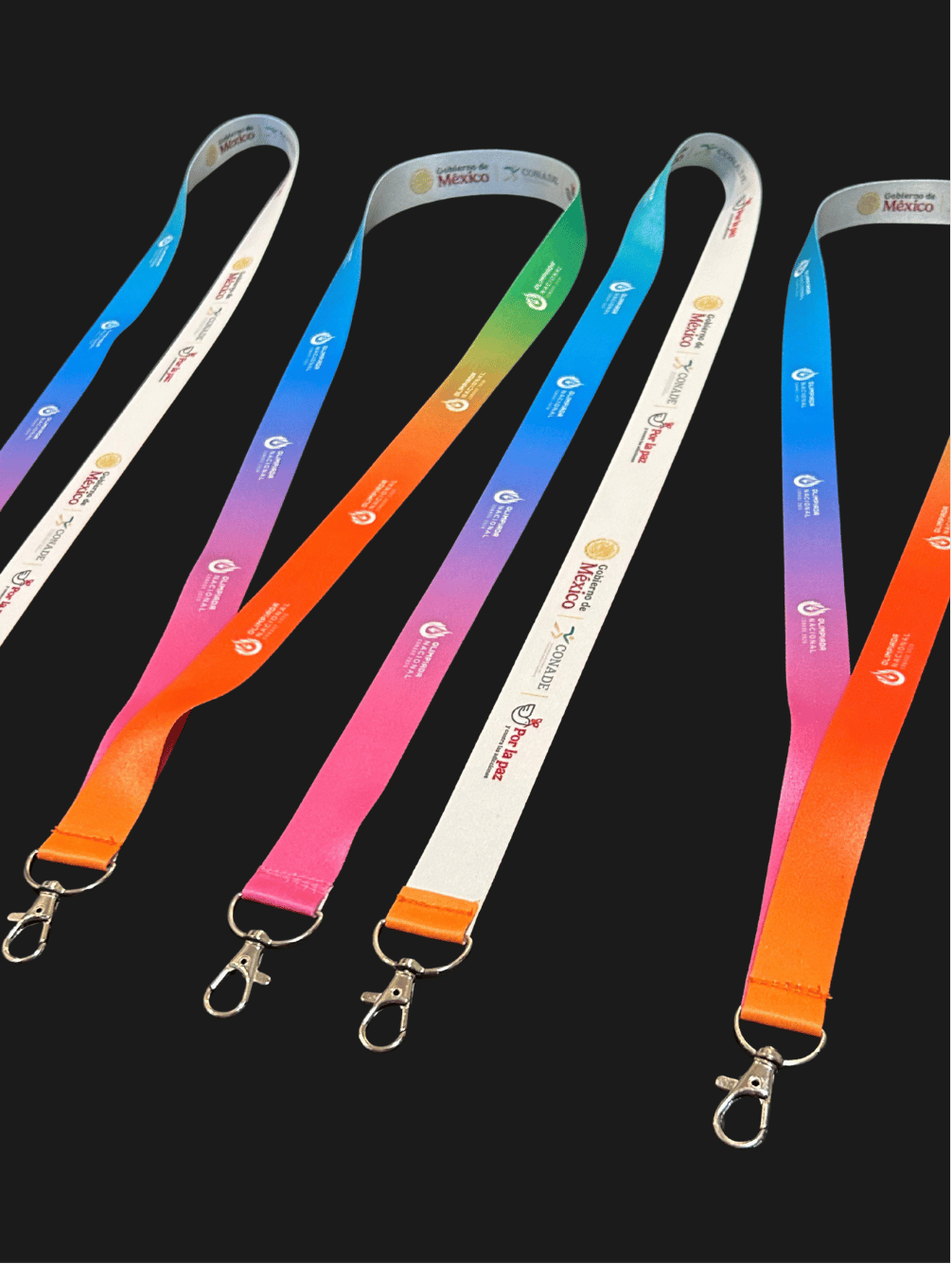 Lanyards personalizados para empresas y eventos, con logotipos y diseños impresos a color, broches metálicos y accesorios de identificación sobre fondo negro.