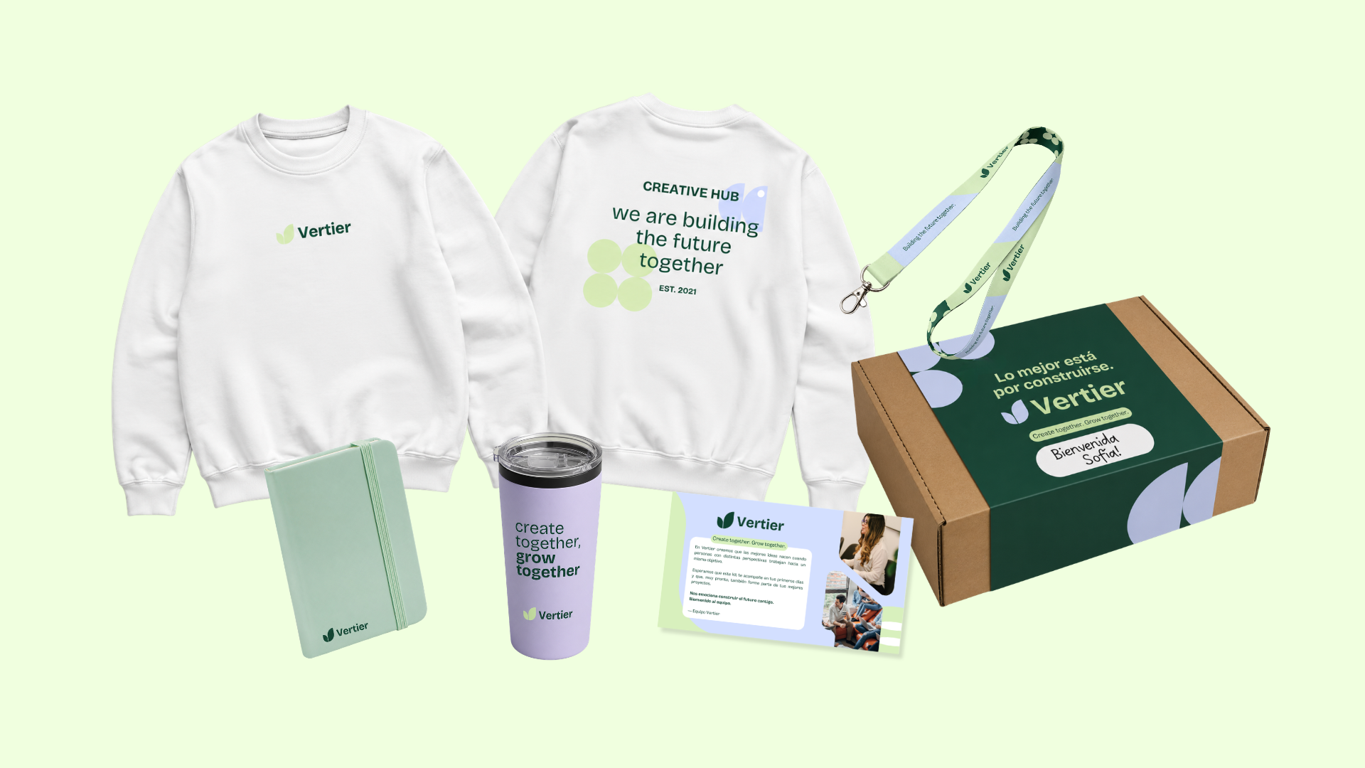 Conjunto de productos de la marca Vertier: sudaderas blancas, una libreta, una taza, un llavero, un folleto y una caja de cartón. Todos con el logotipo y colores de la marca.