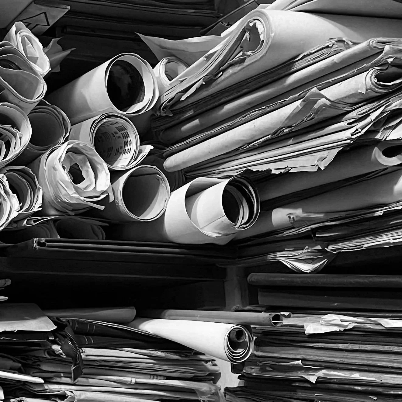 A large pile of crumpled and rolled papers and blueprints on shelves or tables.
