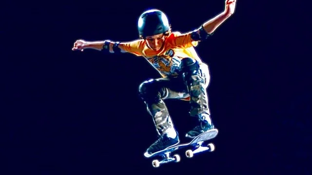 Child wearing helmet skateboarding at night.