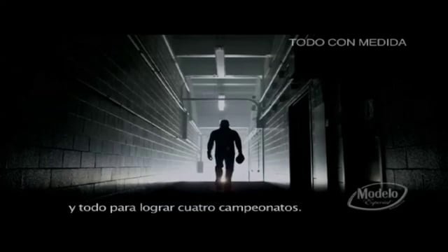 Silhouette of a man walking through a dimly lit corridor with light at the end, holding a helmet, with Spanish text "TODO CON MEDIDA" and "y todo para lograr cuatro campeonatos."