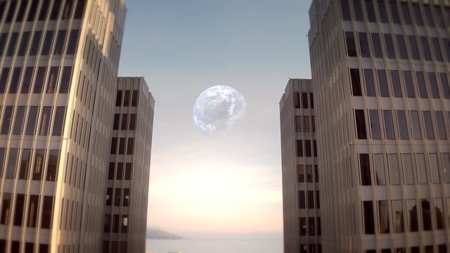 Cityscape with tall office buildings and a large full moon in the sky at sunset.