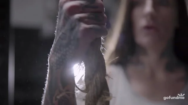 A person holding a snake with bright light behind them, blurred background.