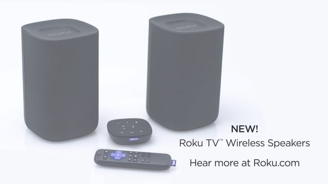 Two Roku TV wireless speakers, a small remote control, and a compact device, possibly a streaming remote, placed on a white surface.