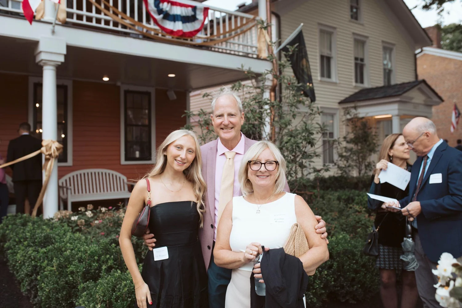 Three guests posing on the front lawn of The Buxton Inn.