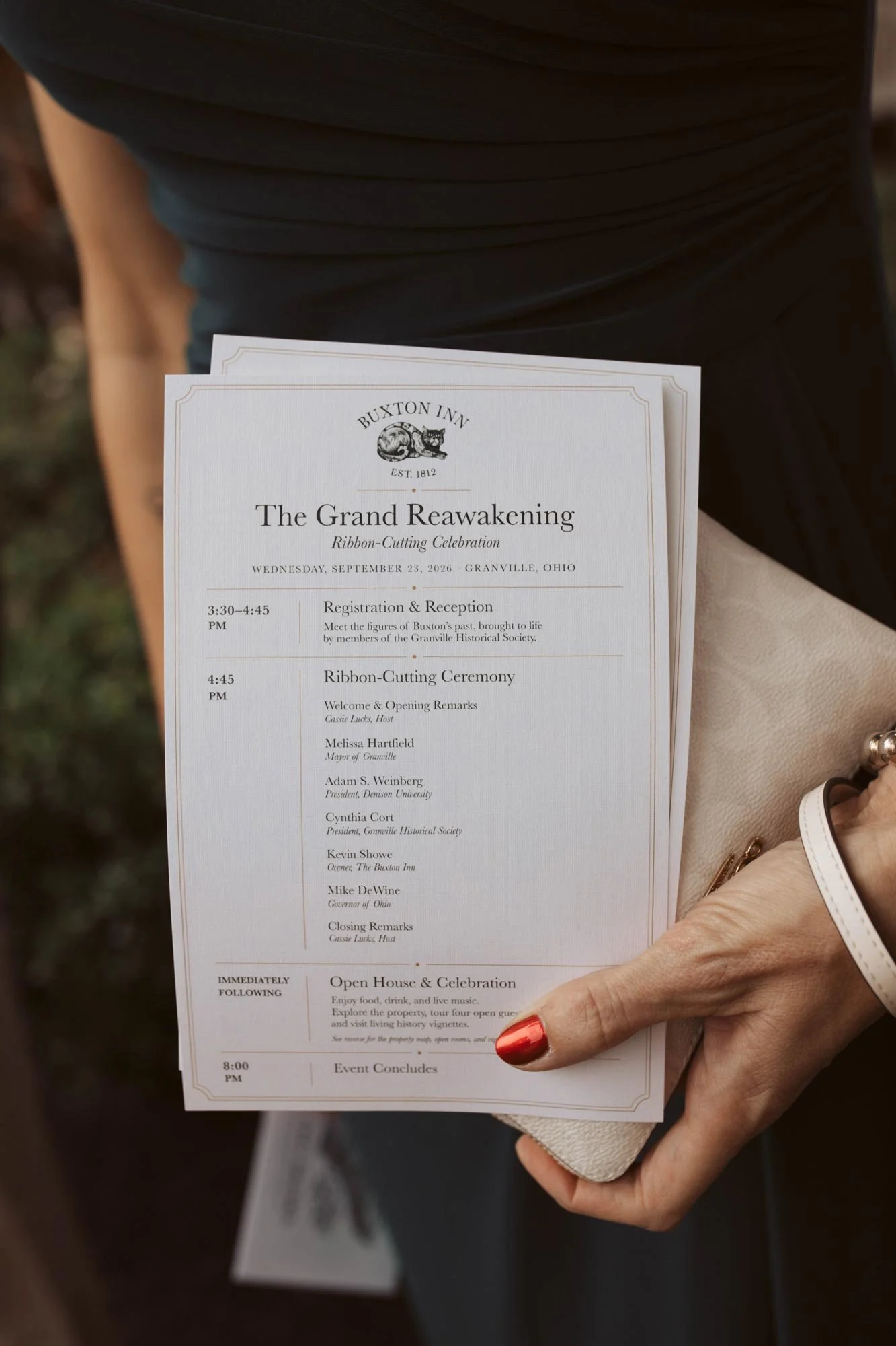 A guest holding the Grand Reawakening event program.