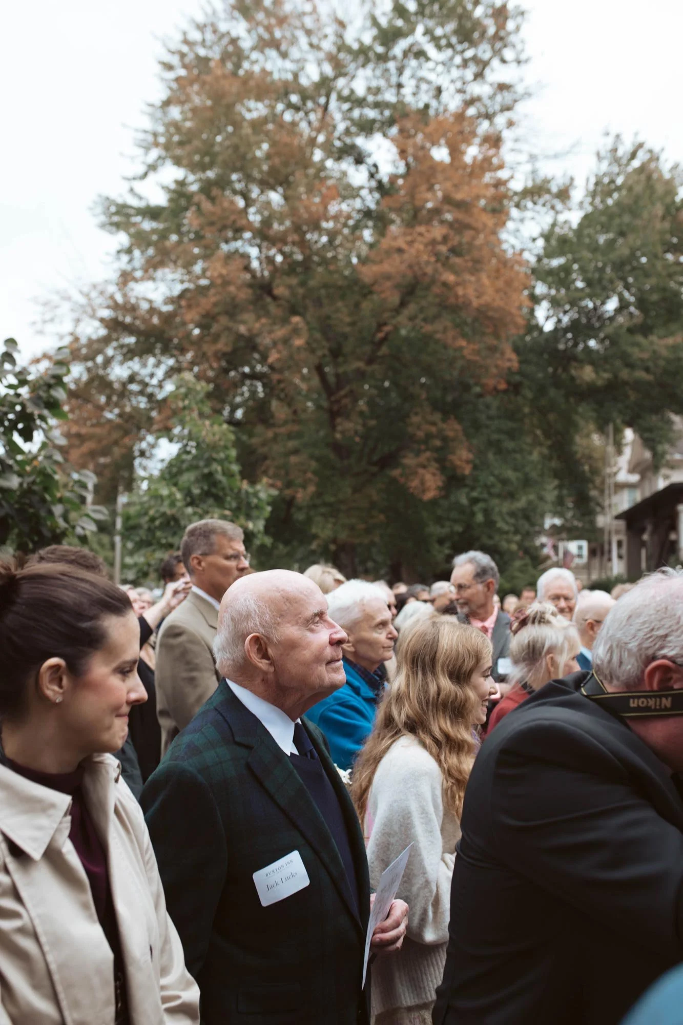 Guests watching the ceremony from beneath the trees.