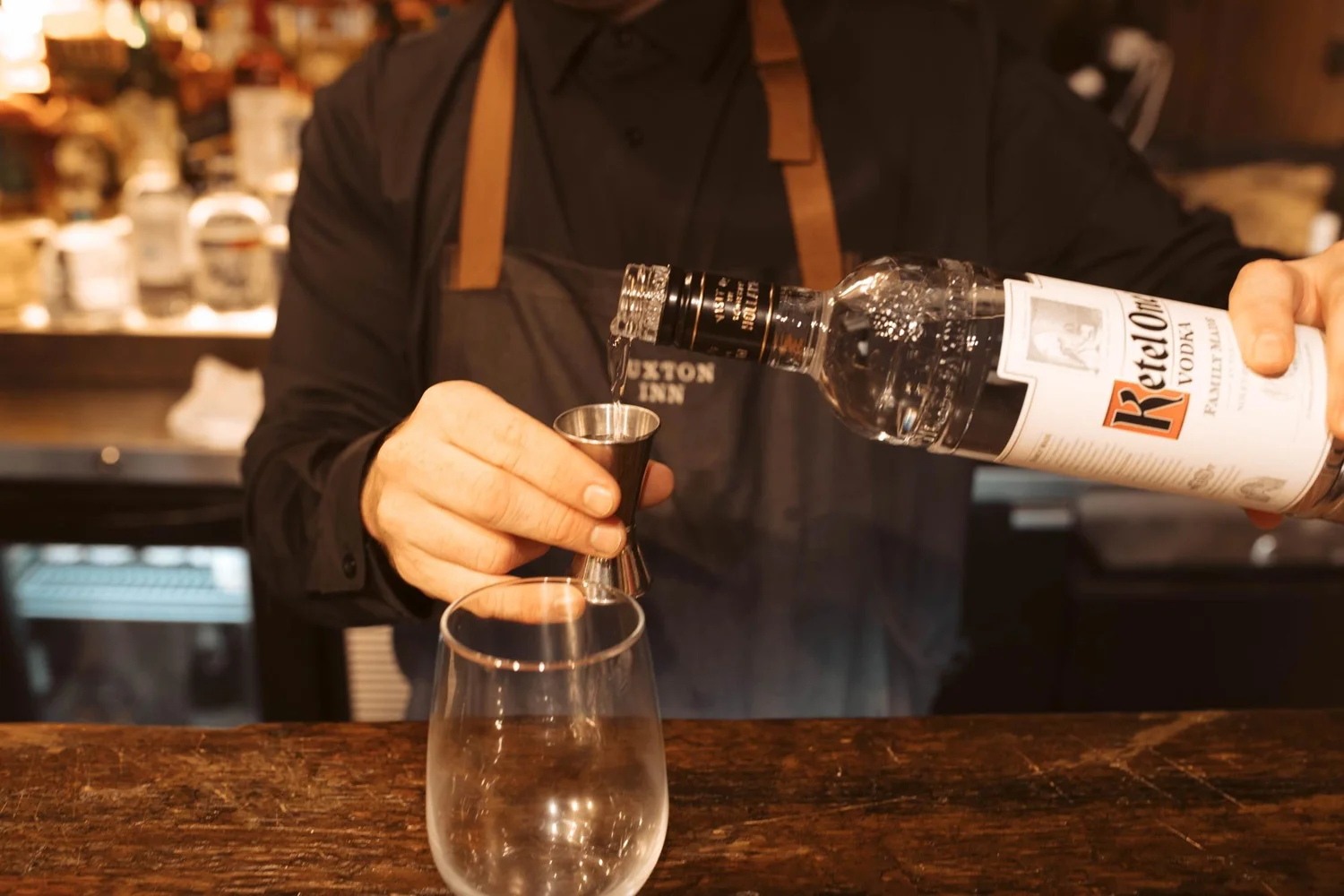 A bartender measuring a pour for a cocktail.