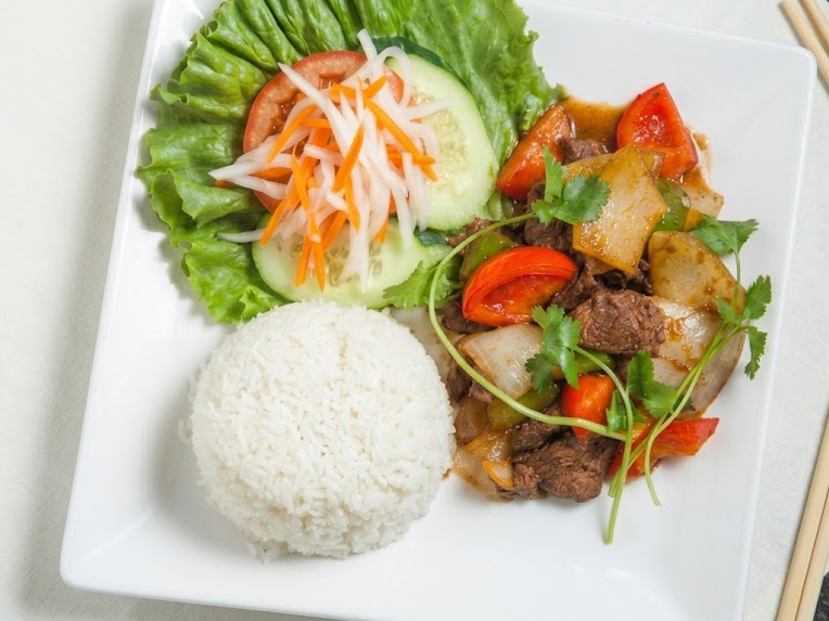 Plate of white rice, beef stir-fry with vegetables, and fresh salad with lettuce, tomato, cucumber, and shredded carrots on a white square plate.