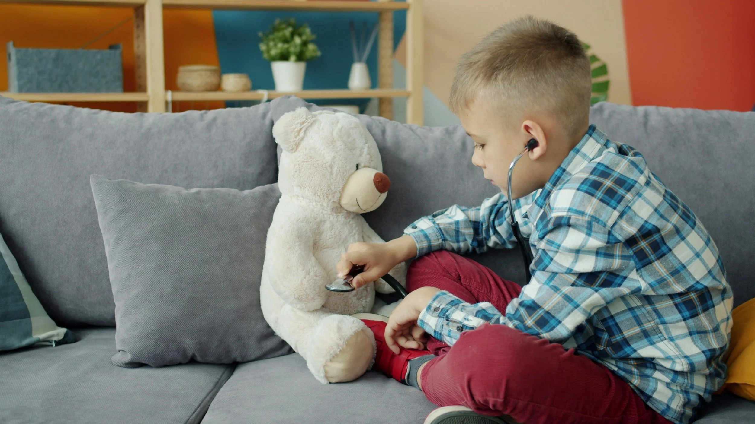young boy using stethoscope on bear, play therapy