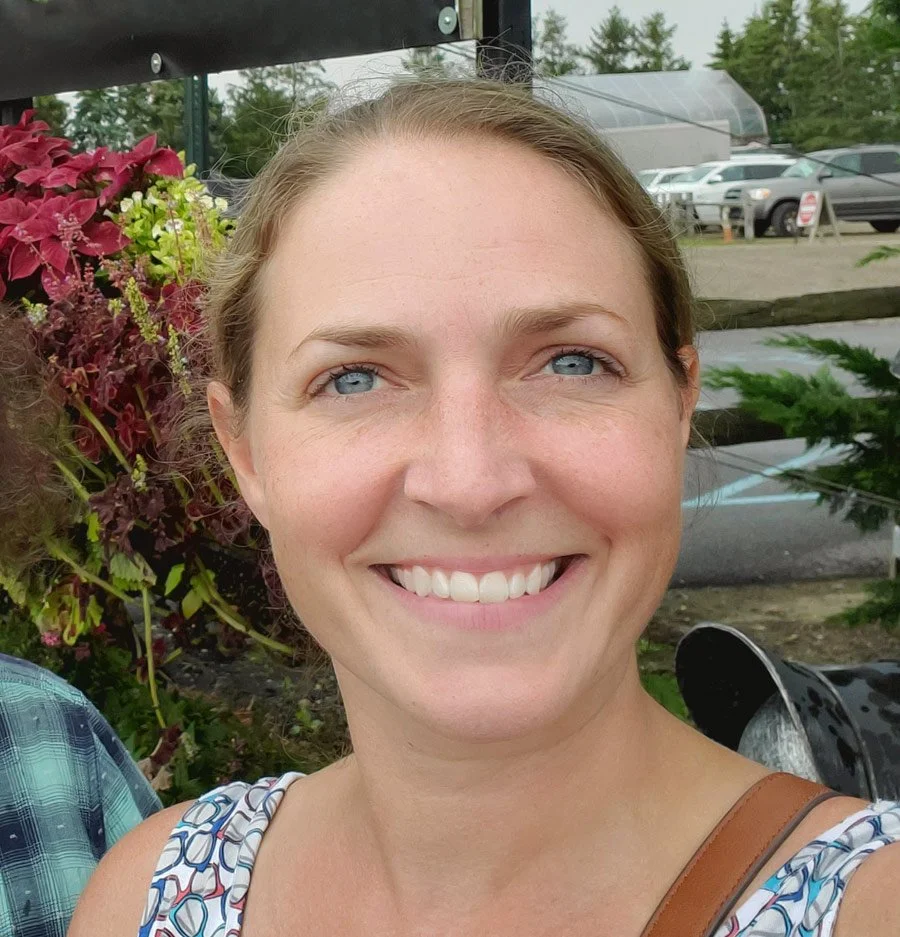 Close-up of a smiling woman with blue eyes and light brown hair.