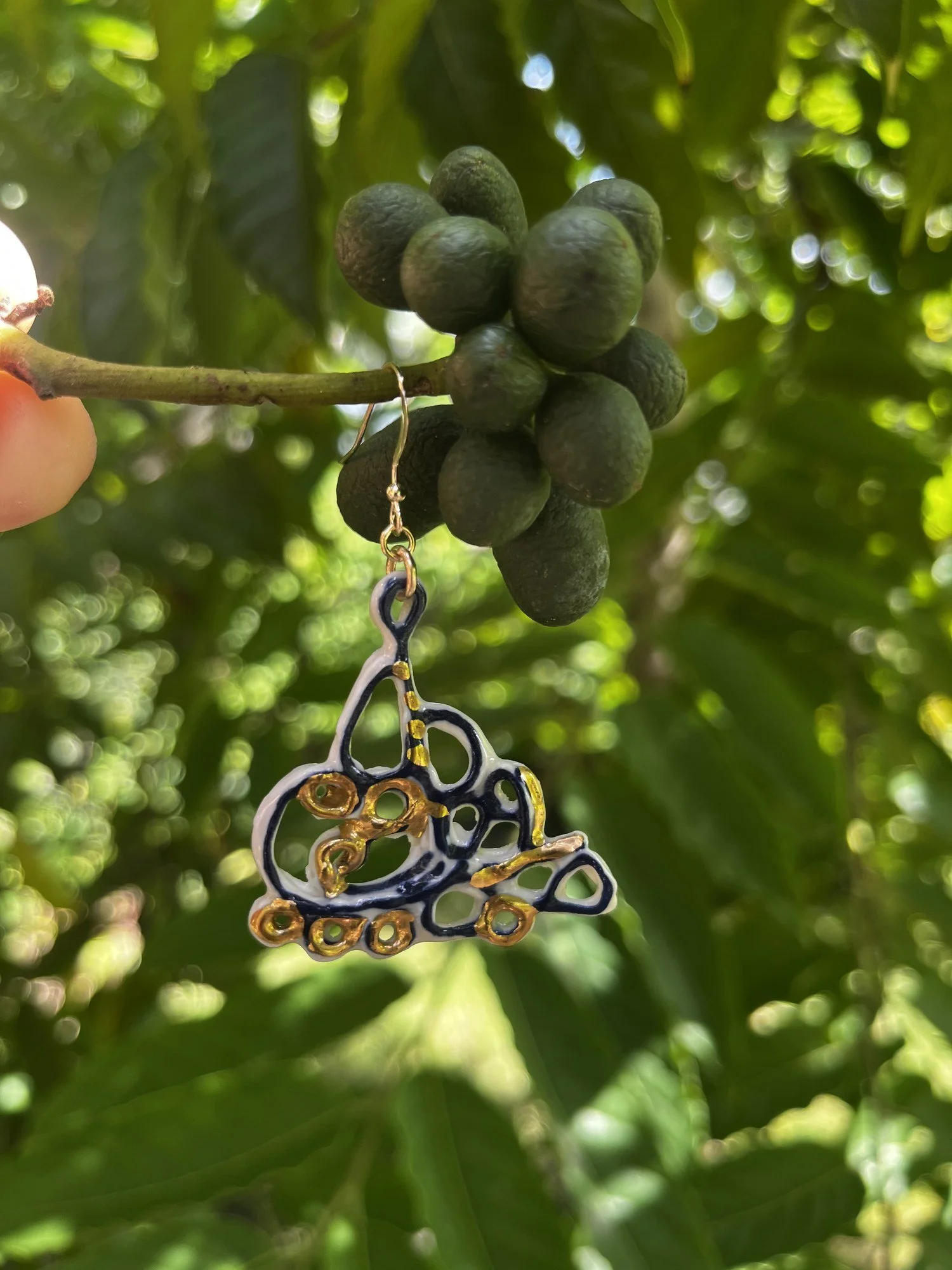 Porcelain earring No. 007 in cobalt blue and gold luster hanging outdoors