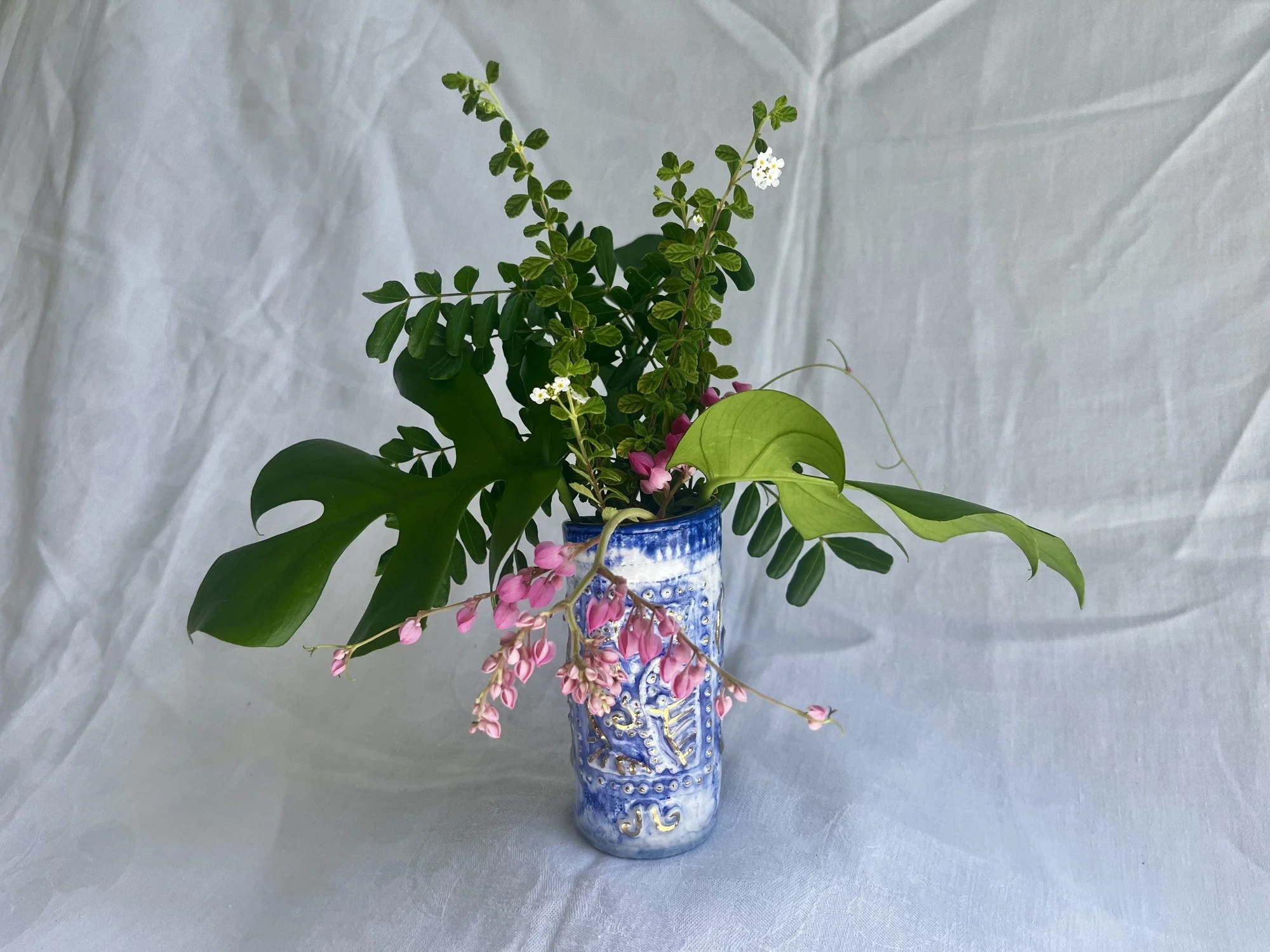 Hand-built porcelain bud vase in cobalt blue and gold luster holding fresh flowers