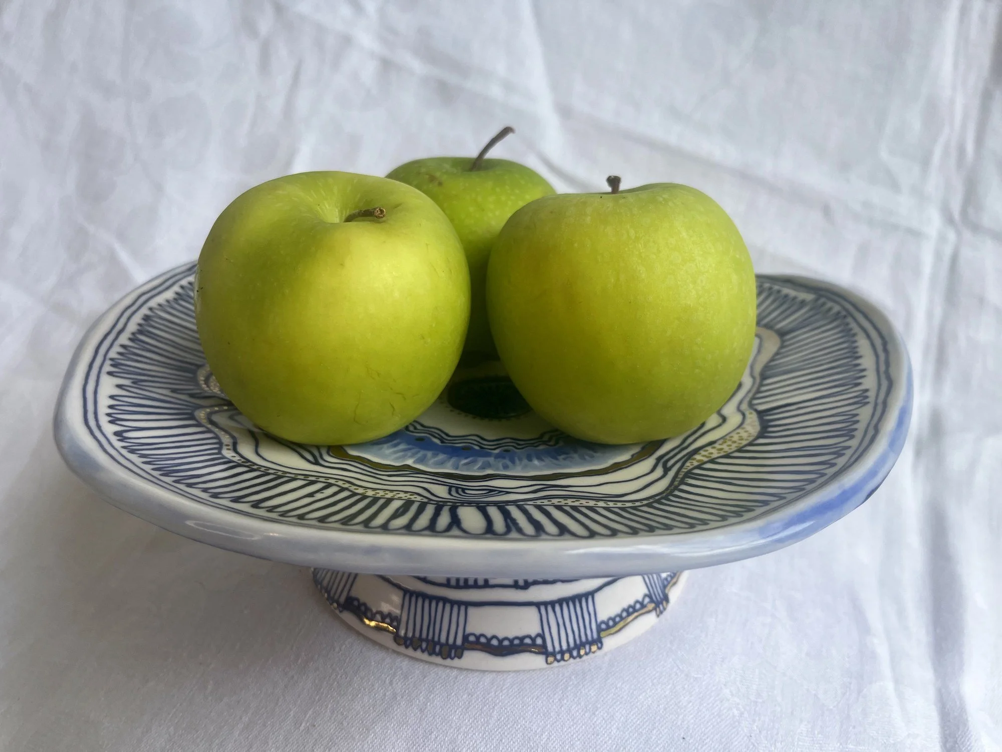 Hand-thrown porcelain footed serving dish holding apples by Cypress Knees Ceramics